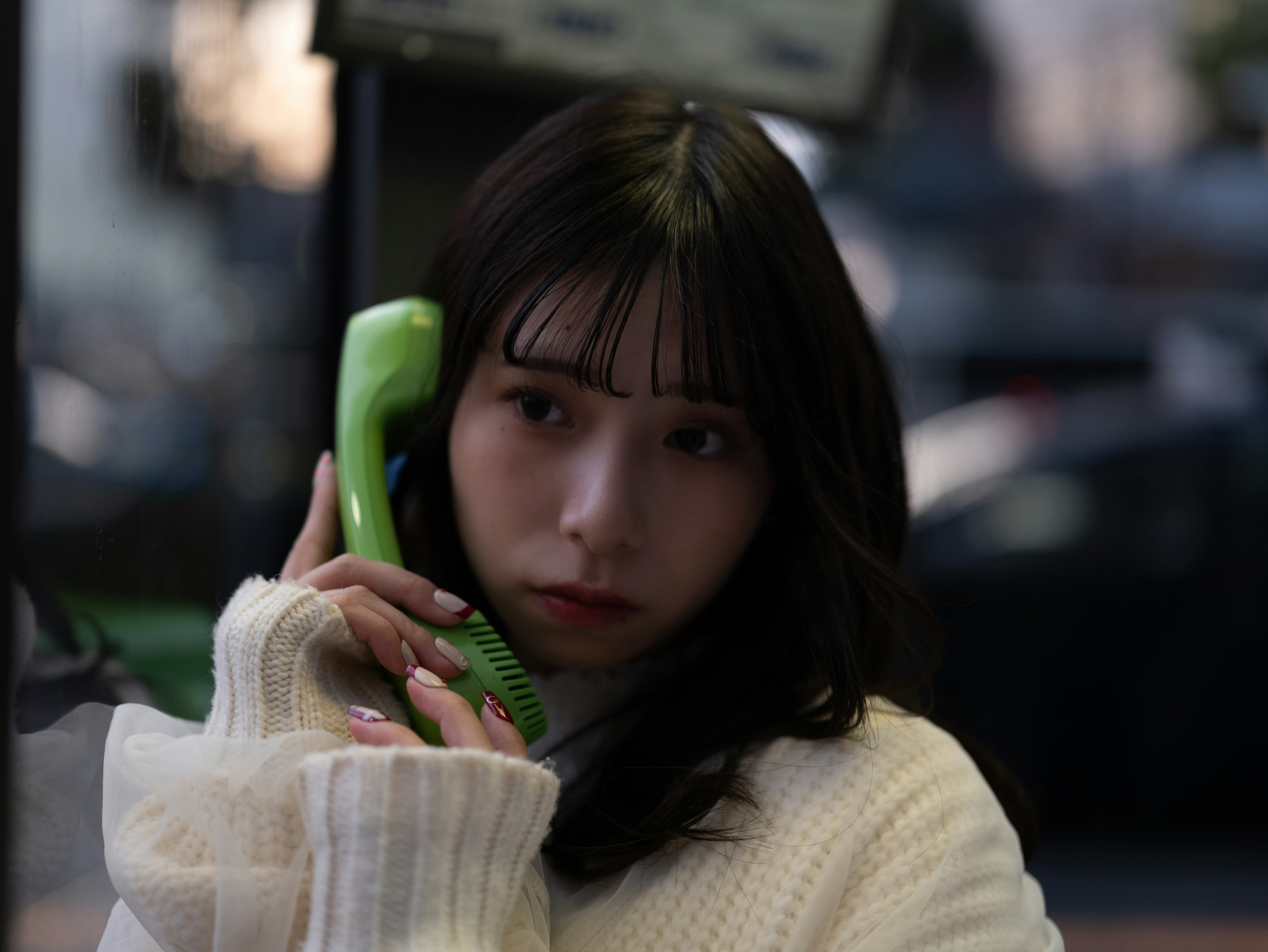 Portrait of a woman holding a green phone receiver against a dark background