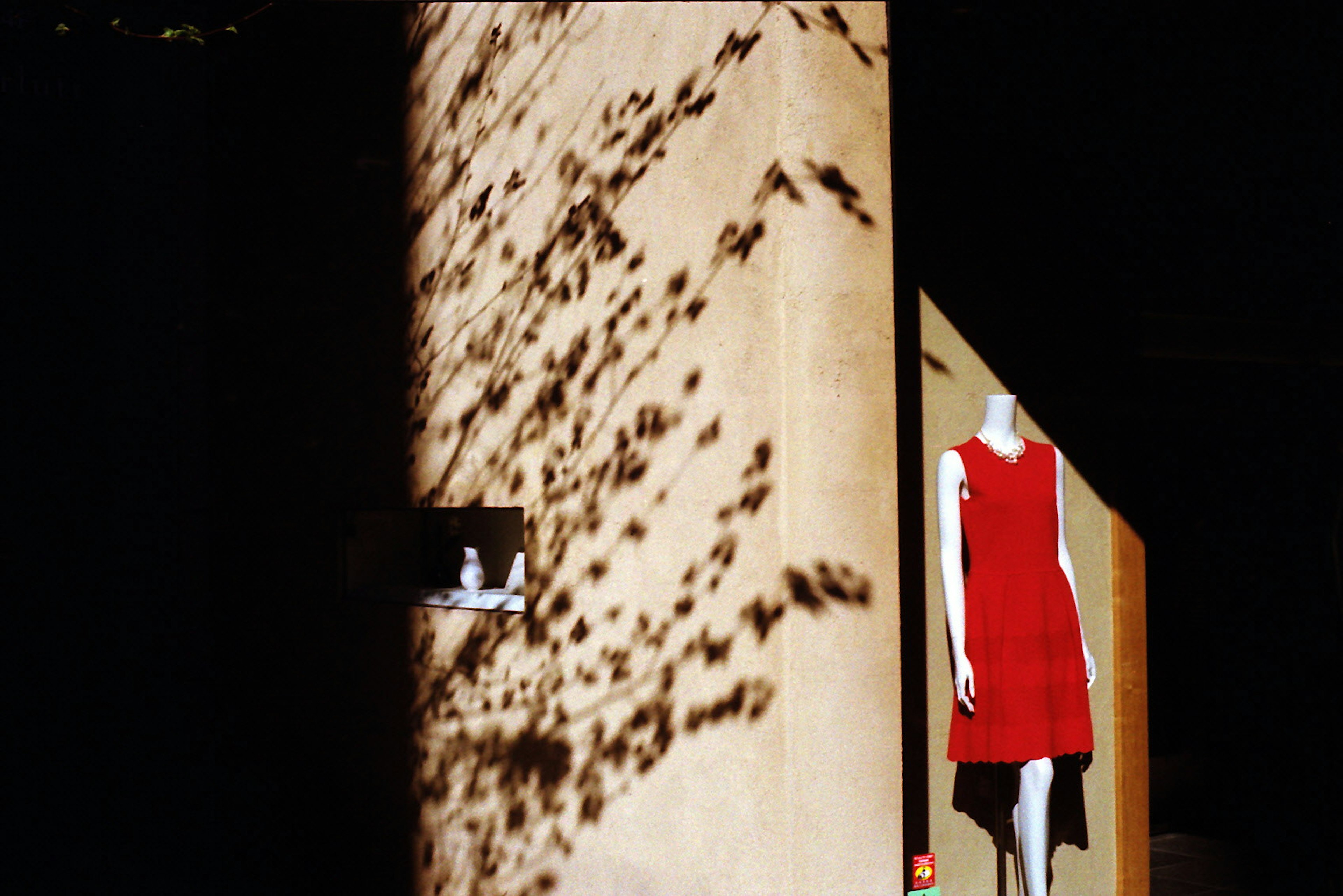 Display space featuring a red dress and shadow patterns on the wall