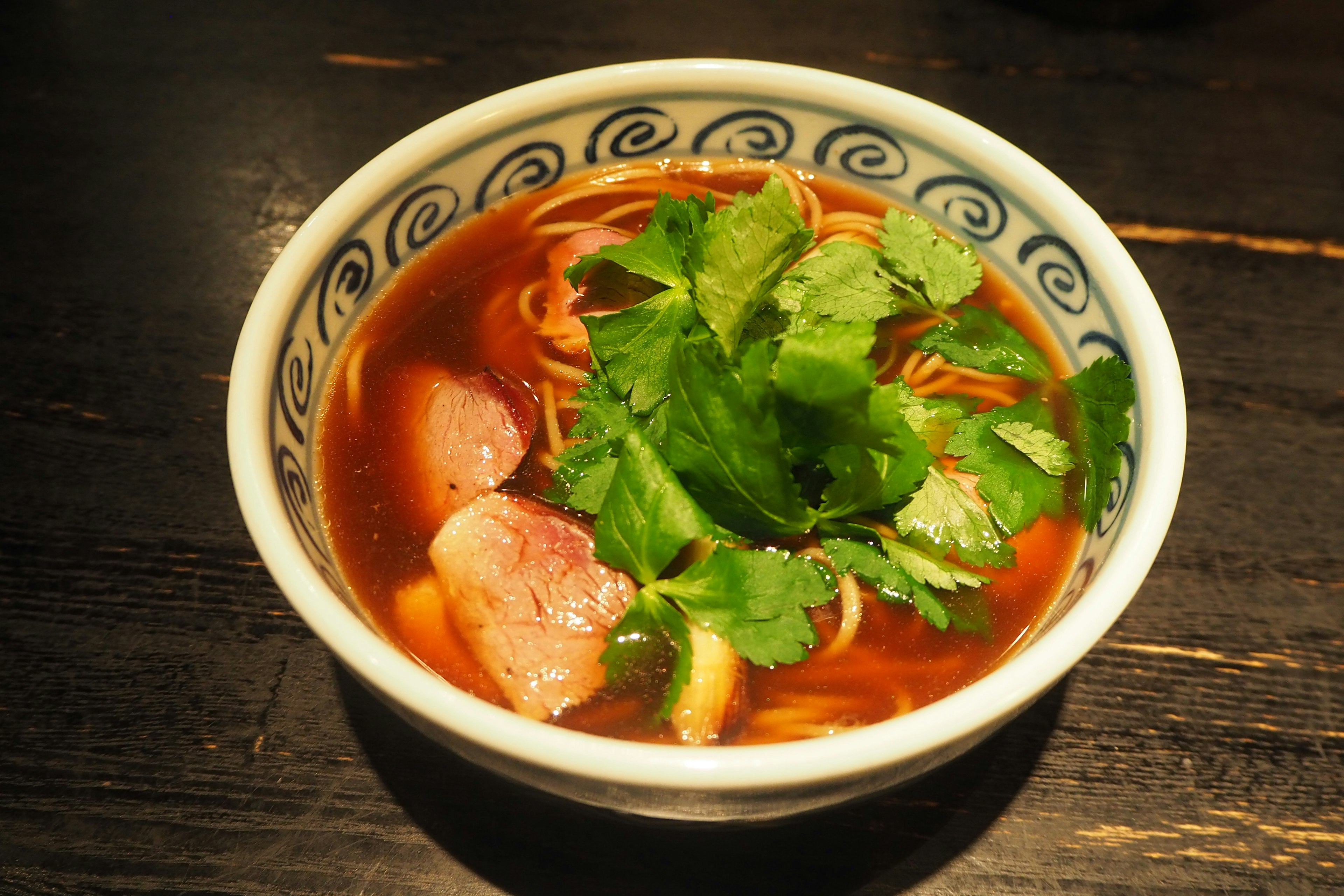 Bowl of ramen with aromatic broth topped with fresh herbs