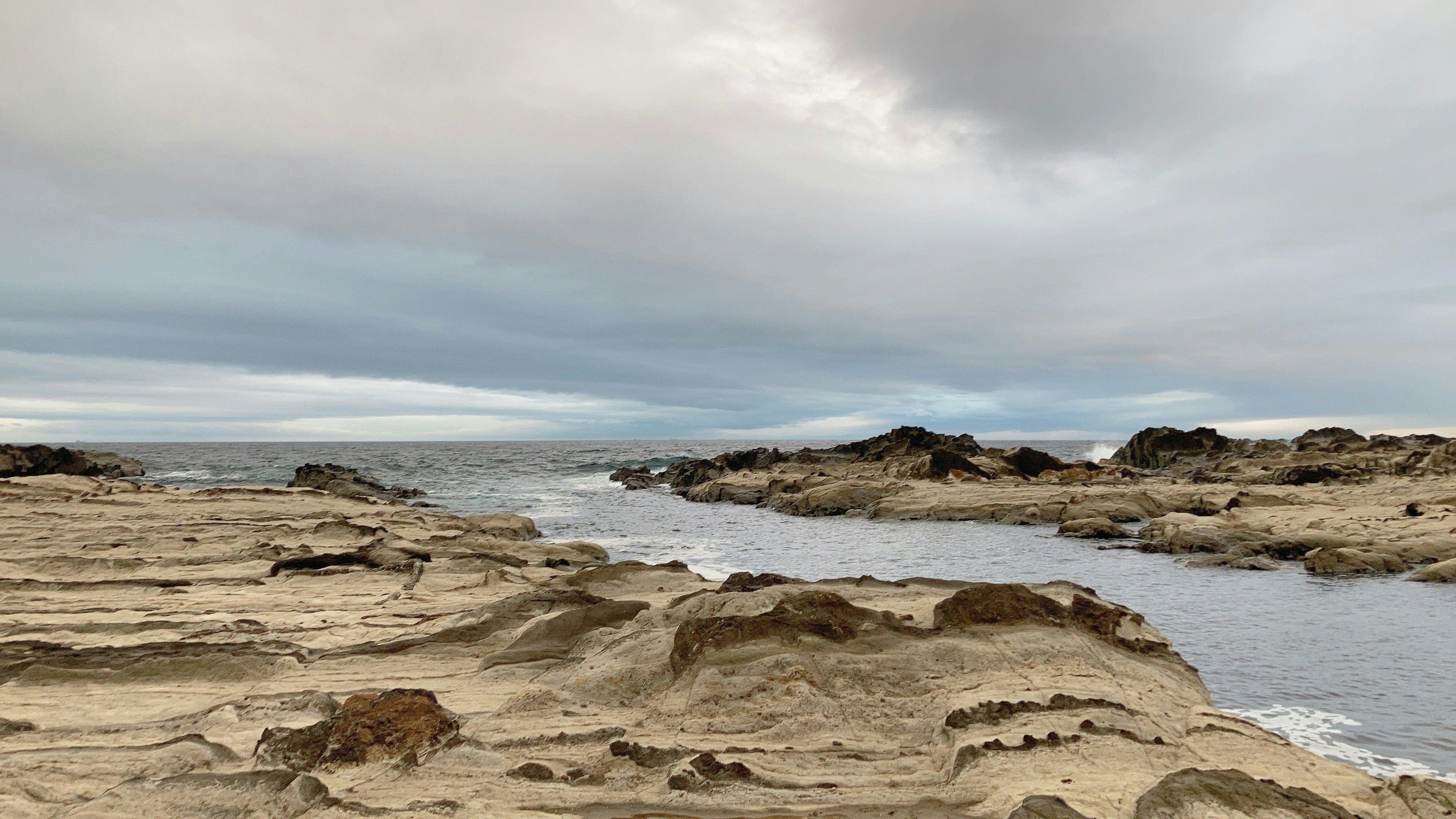 Pemandangan pantai dengan tebing berbatu dan laut tenang