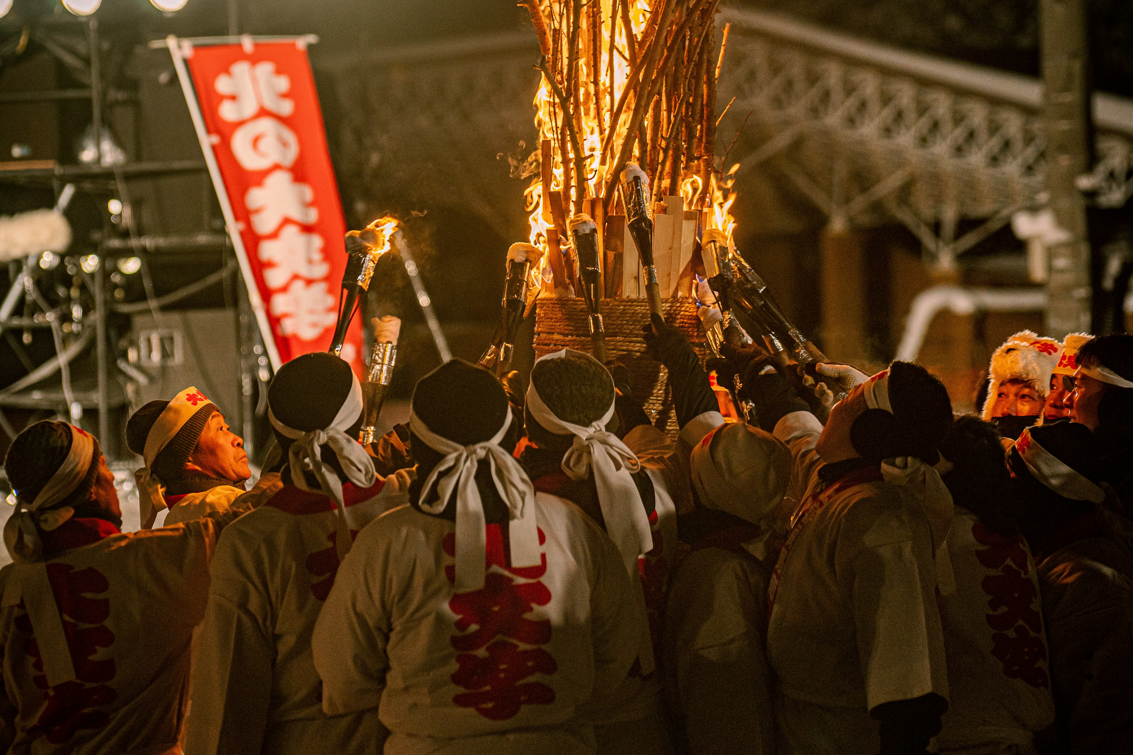 夜の祭りで火を持つ人々の集まりと赤い旗