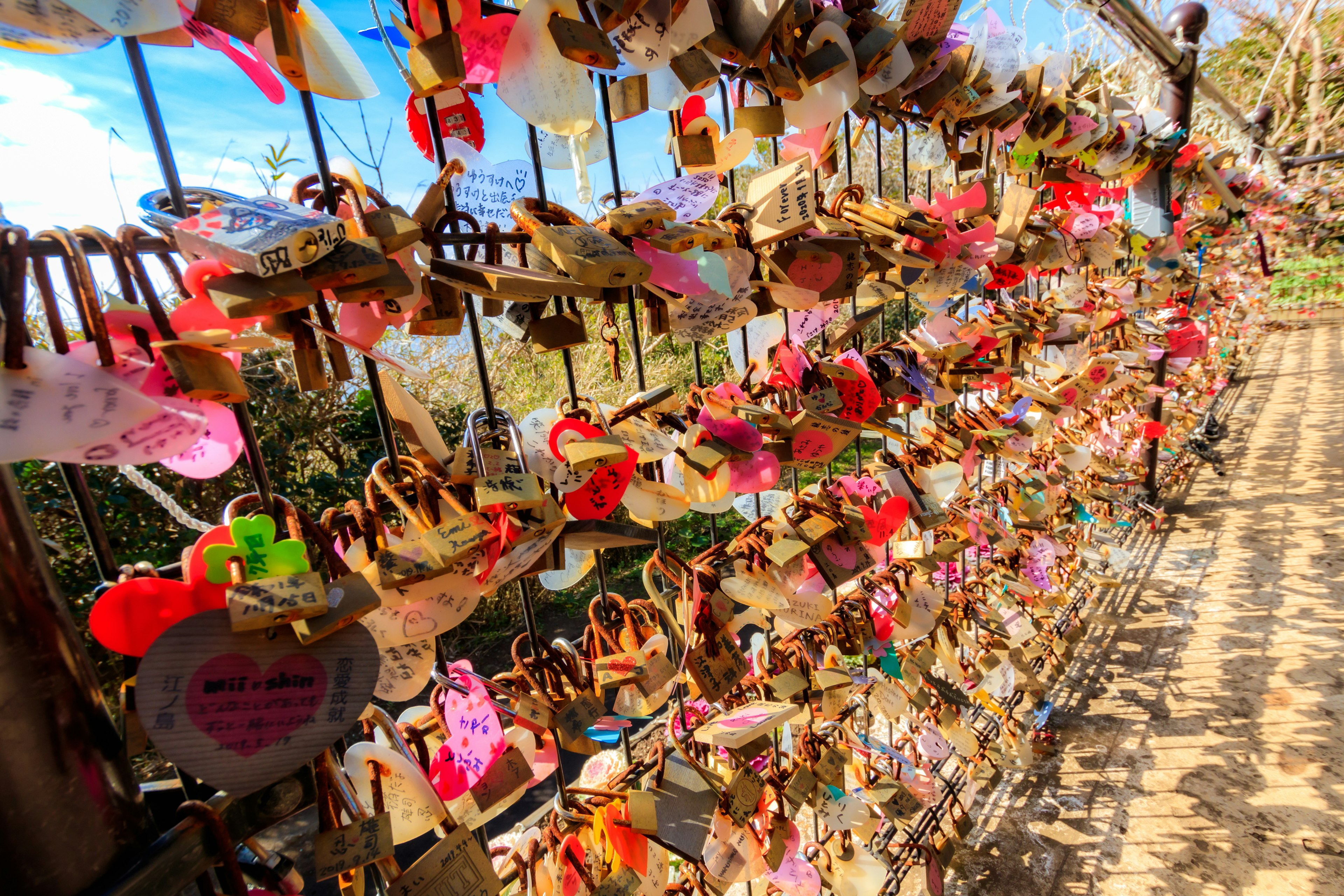 Una vista di una recinzione decorata con lucchetti d'amore e messaggi