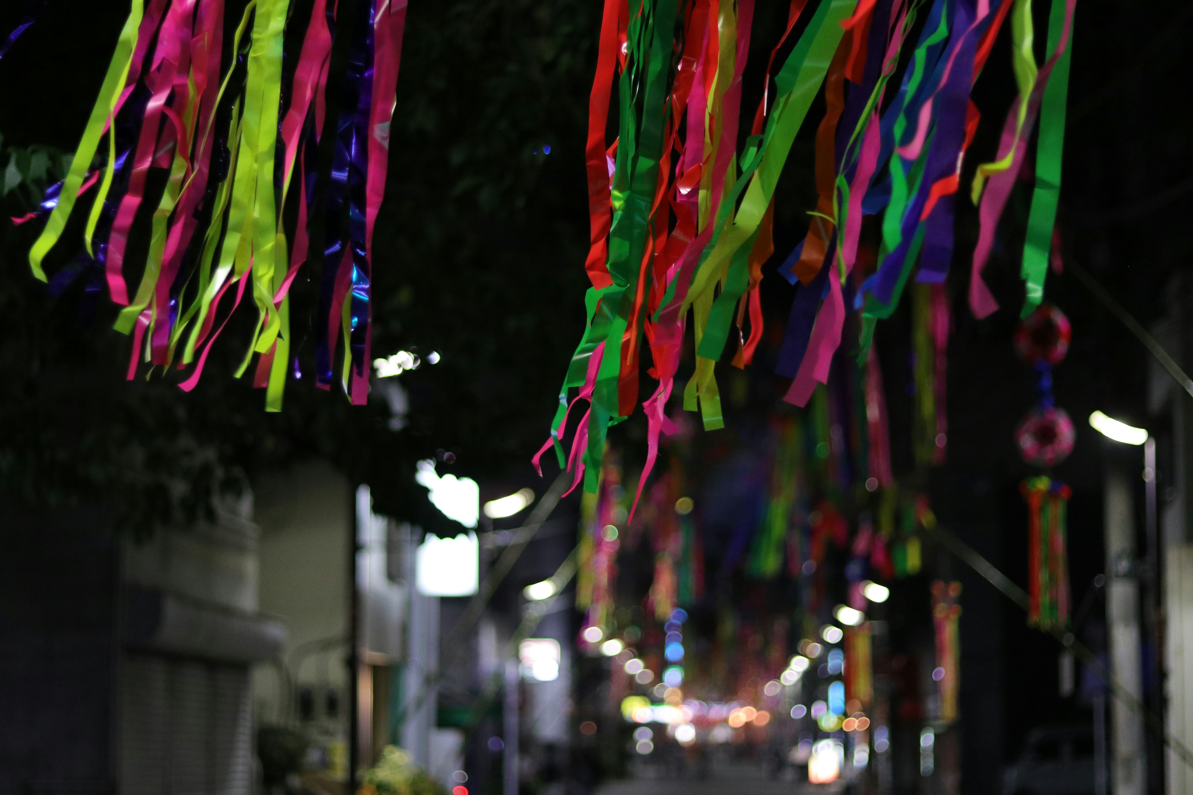 Des rubans colorés suspendus dans une rue nocturne