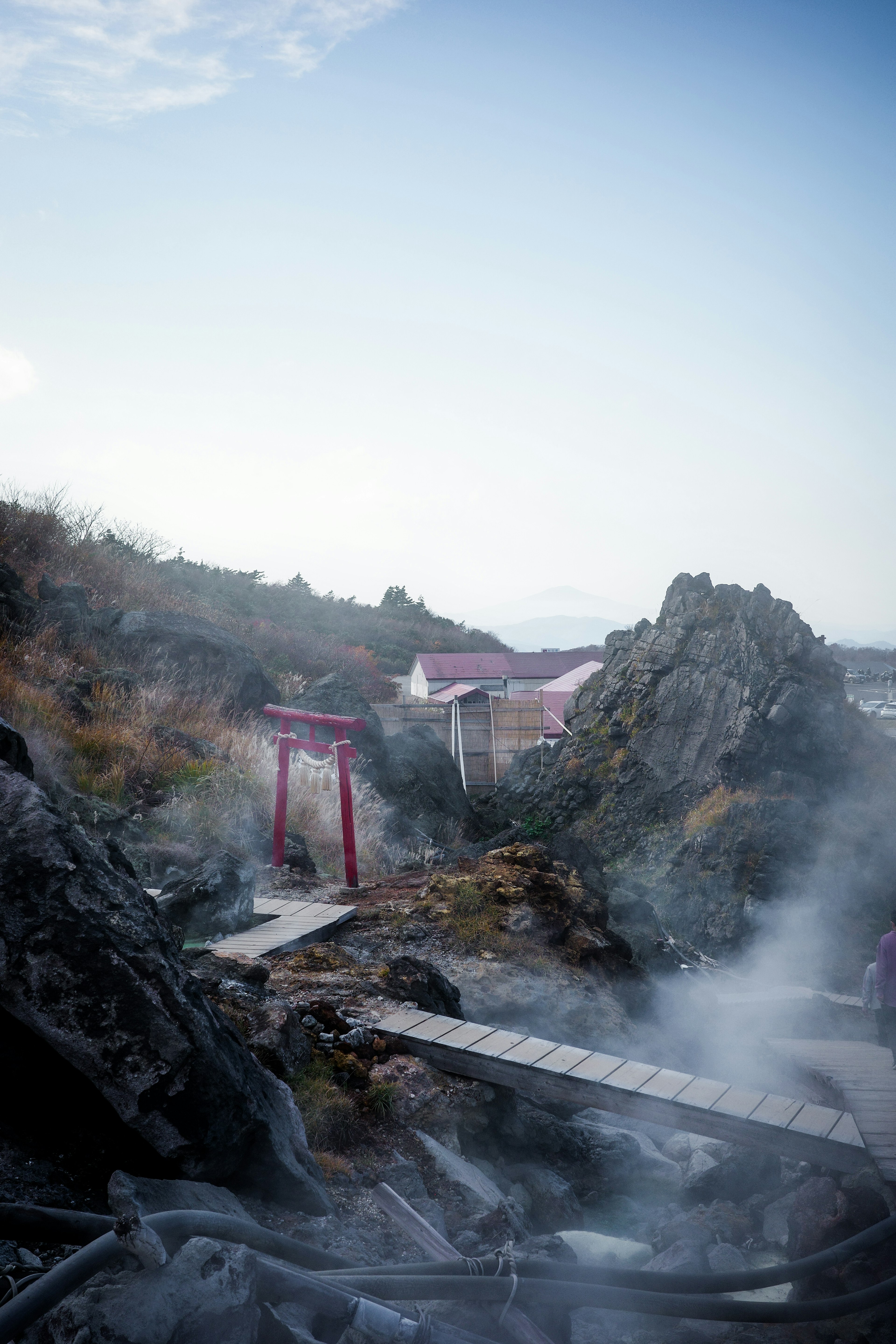 Paisaje con torii rojos y vapor de aguas termales en terreno rocoso