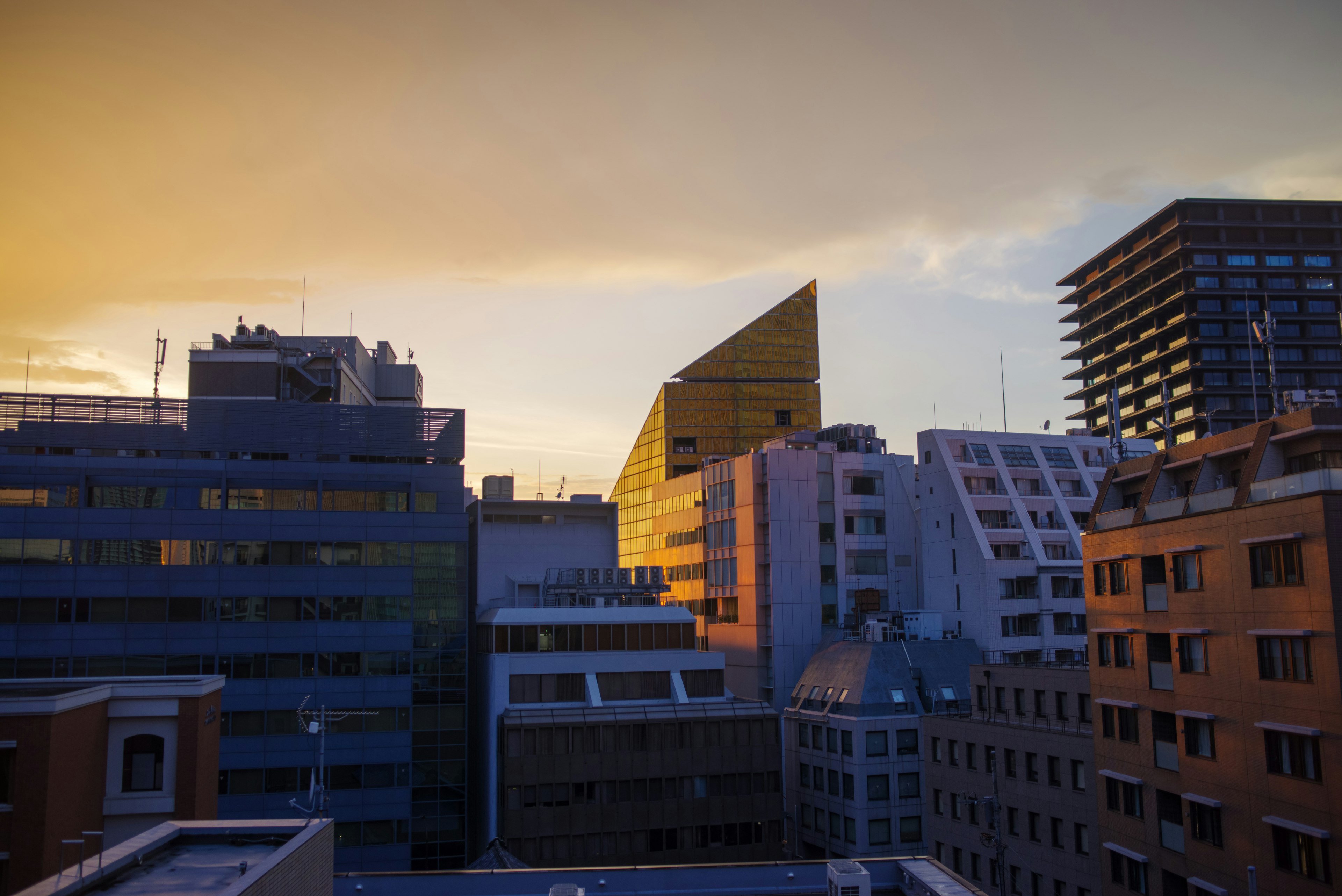 Modern buildings with unique roofs against a sunset sky