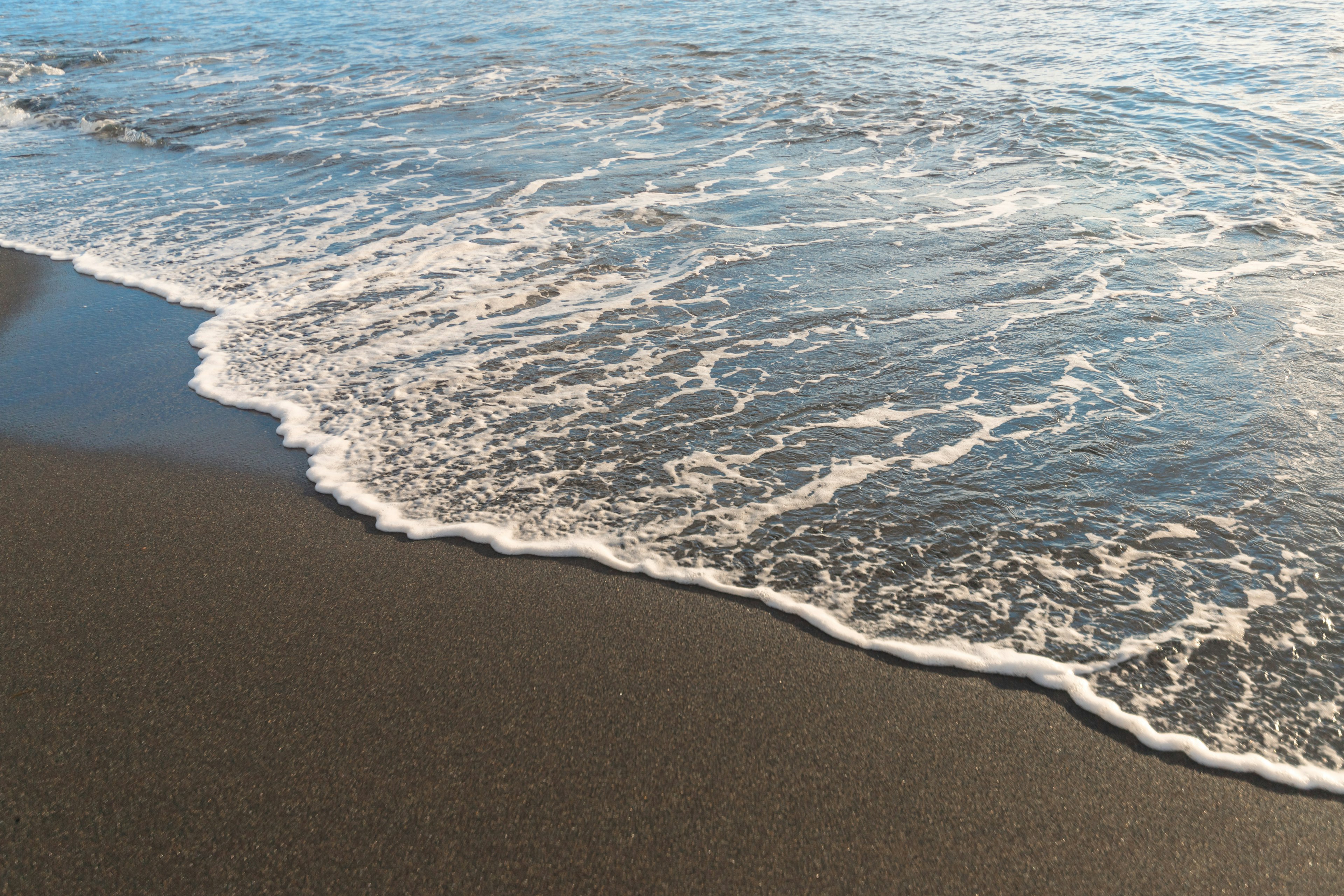 Des vagues se brisant doucement sur une plage de sable