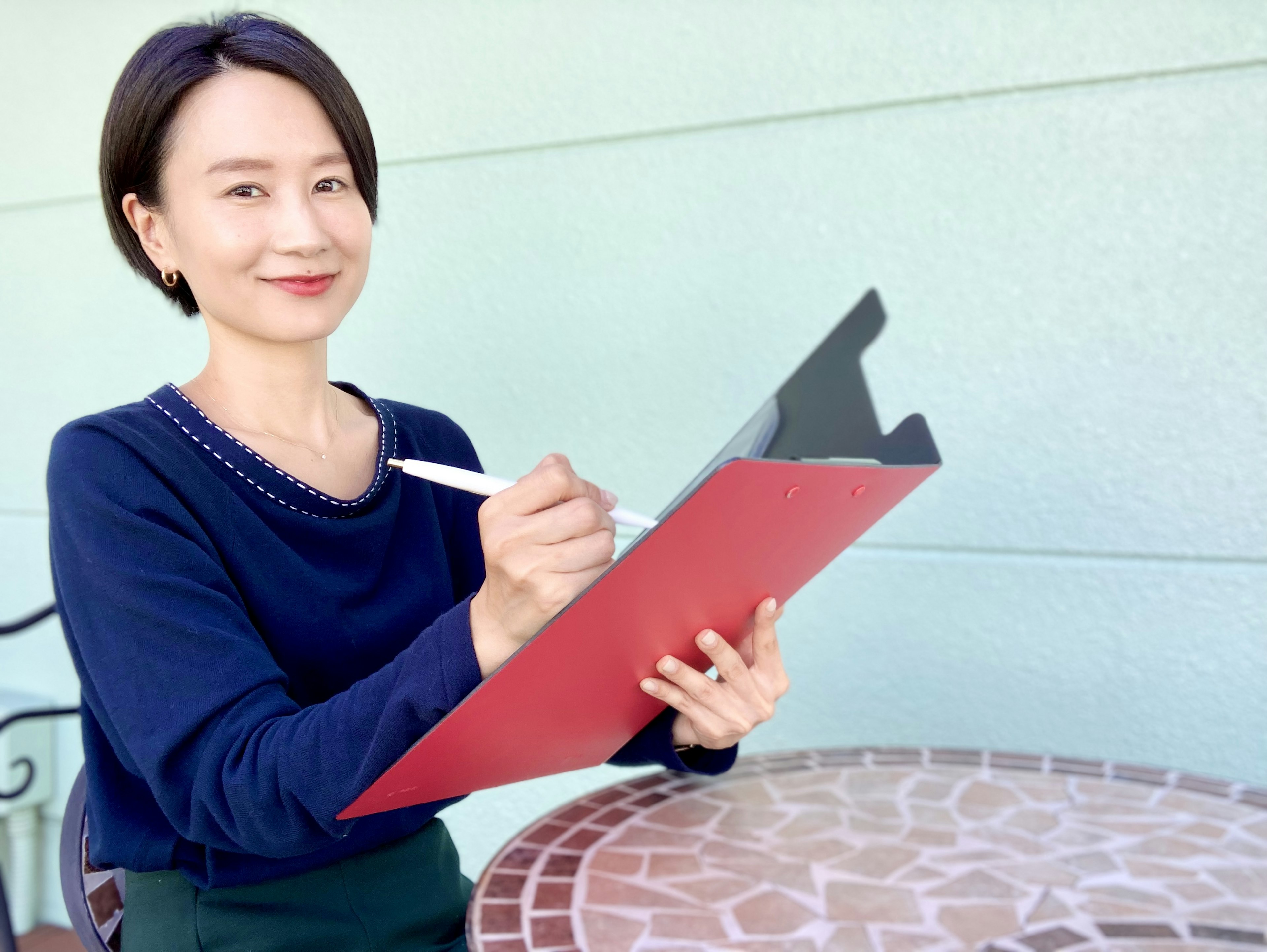 Mujer sonriendo mientras sostiene un clipboard rojo