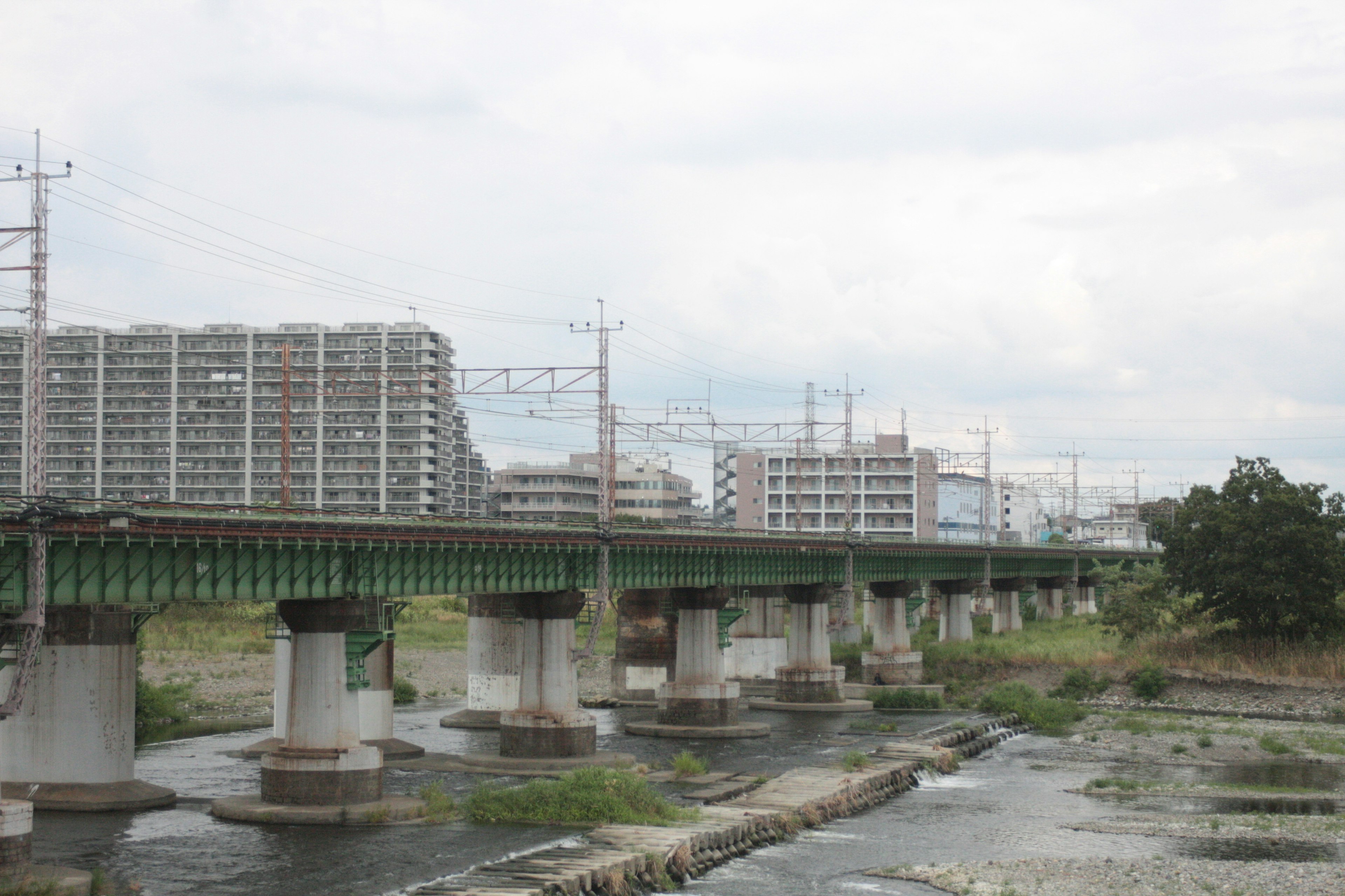 Vista de una vía de tren elevada sobre un río con edificios cercanos