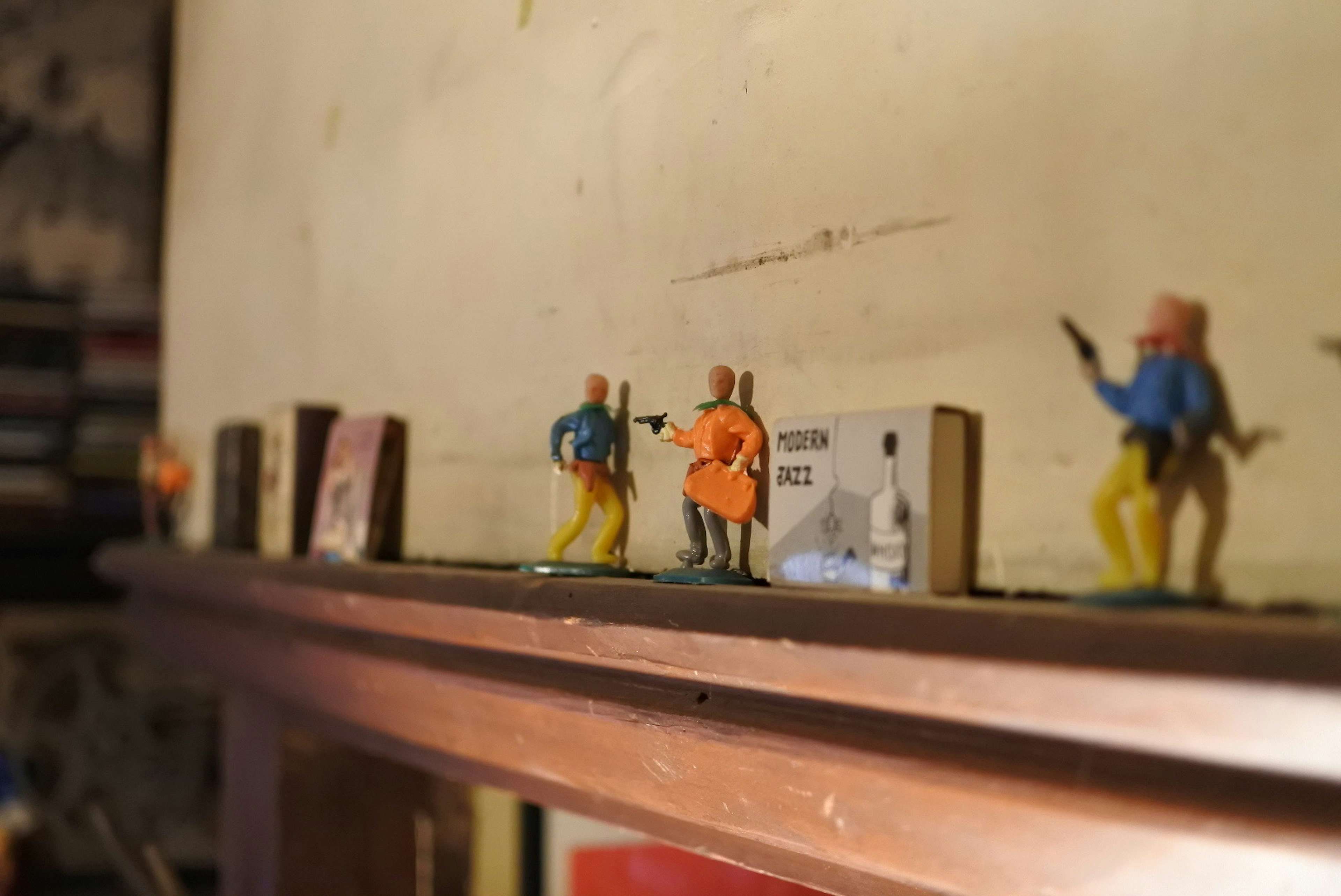 Colorful plastic figures lined up on a shelf with a textured wall in the background