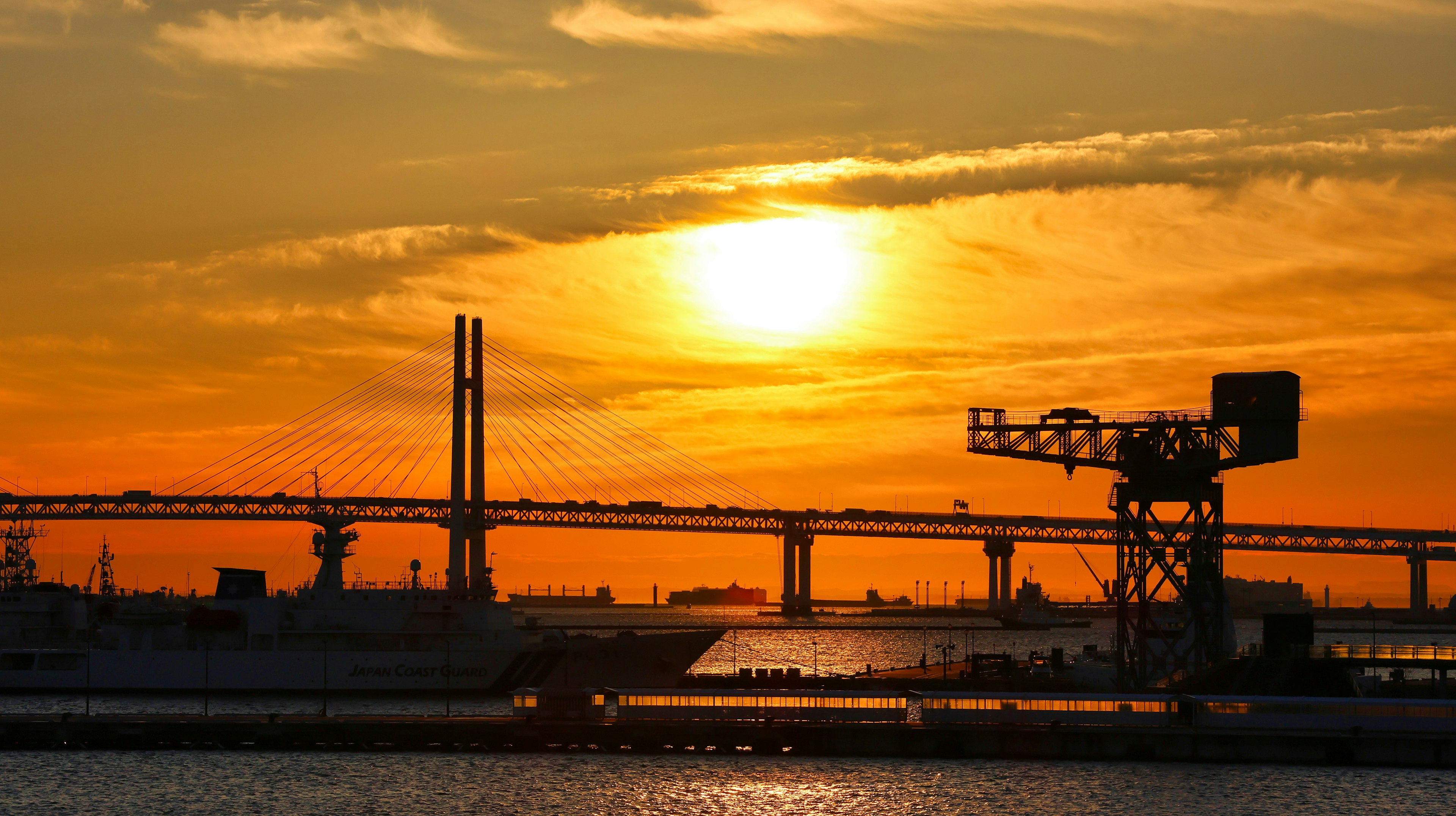 夕日が沈む工業地帯の景色 橋とクレーンが見える