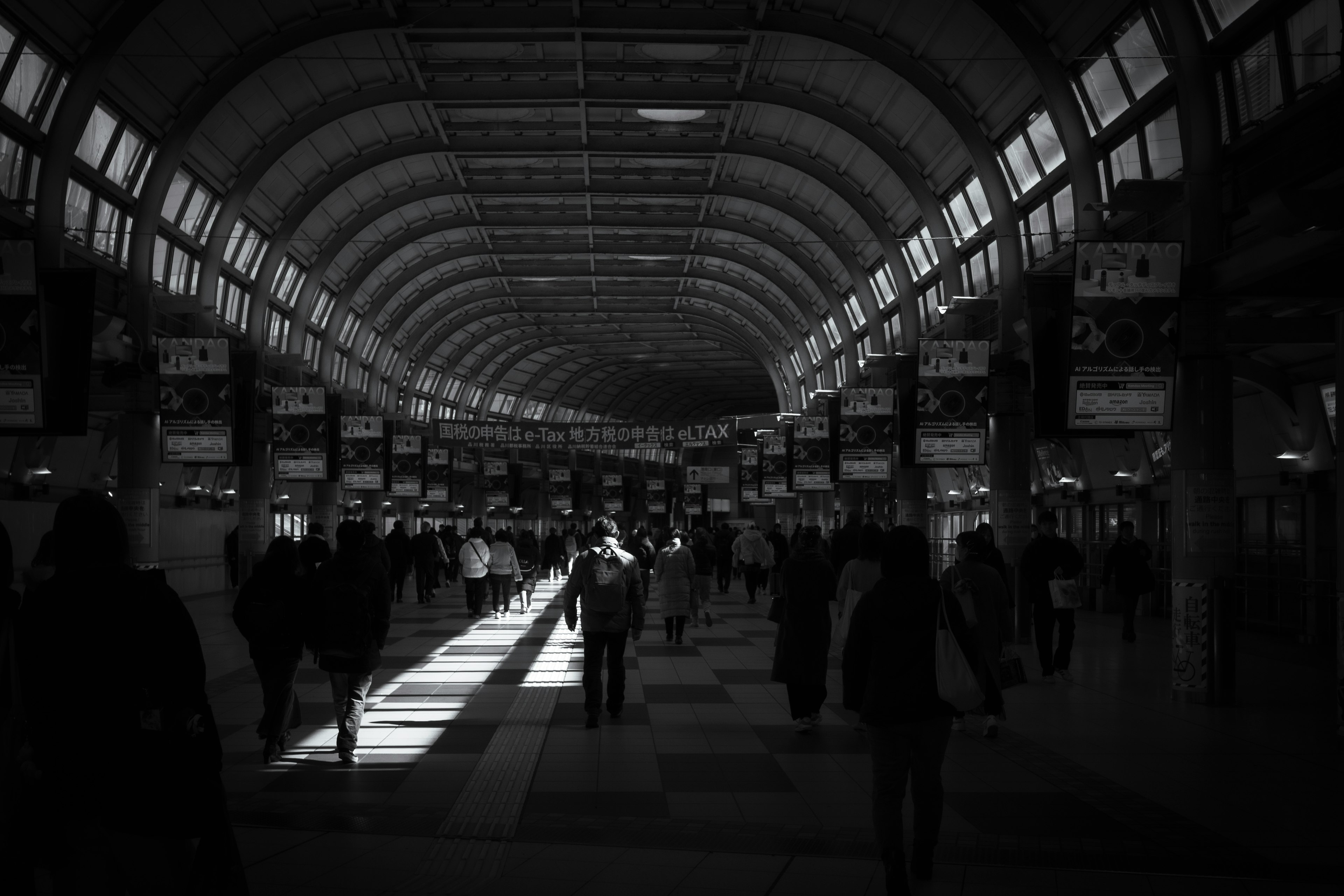 Interior of a dark station with a tunnel-like architecture many people walking