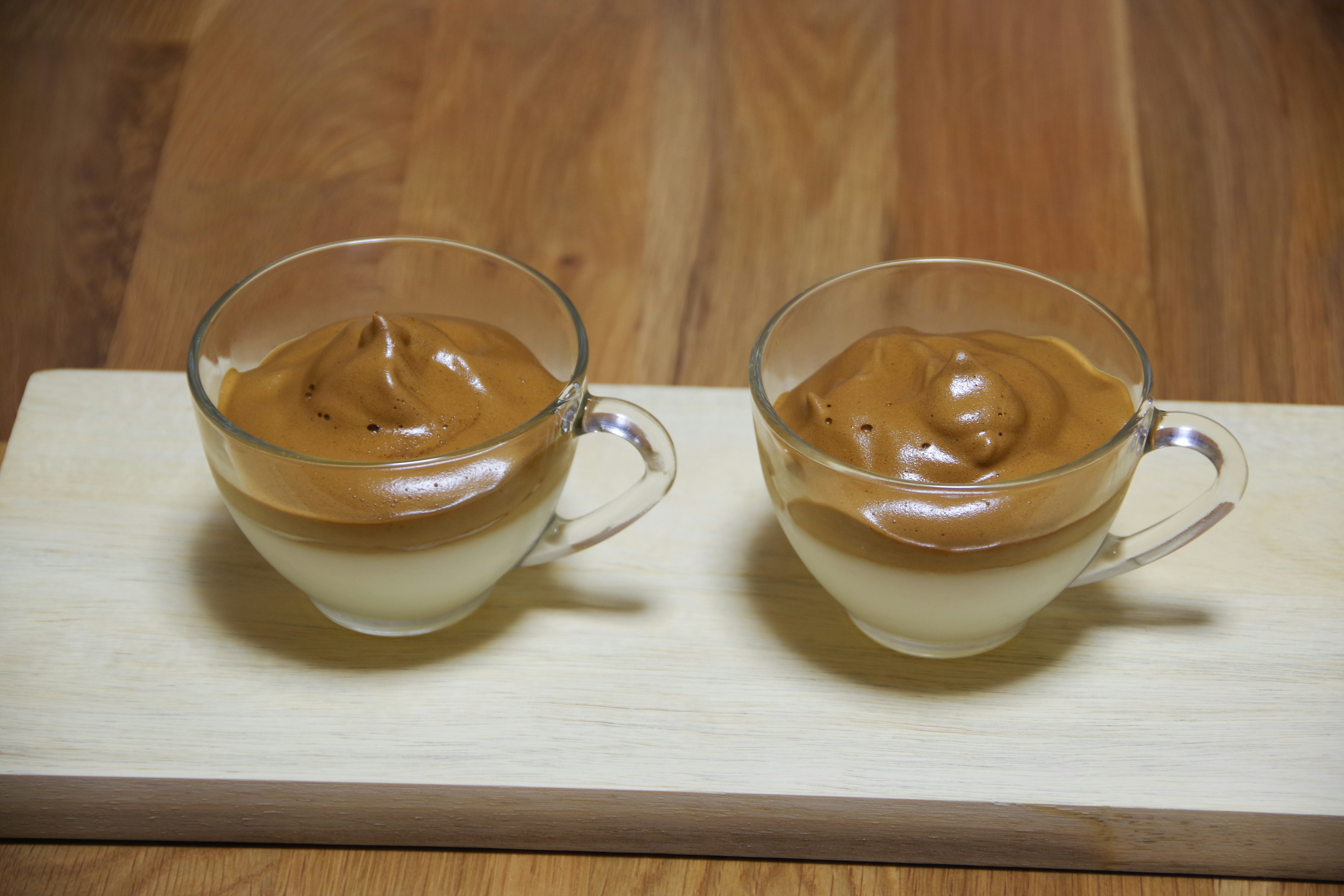 Due tazze di vetro con dessert cremoso guarnito con crema di caffè montata