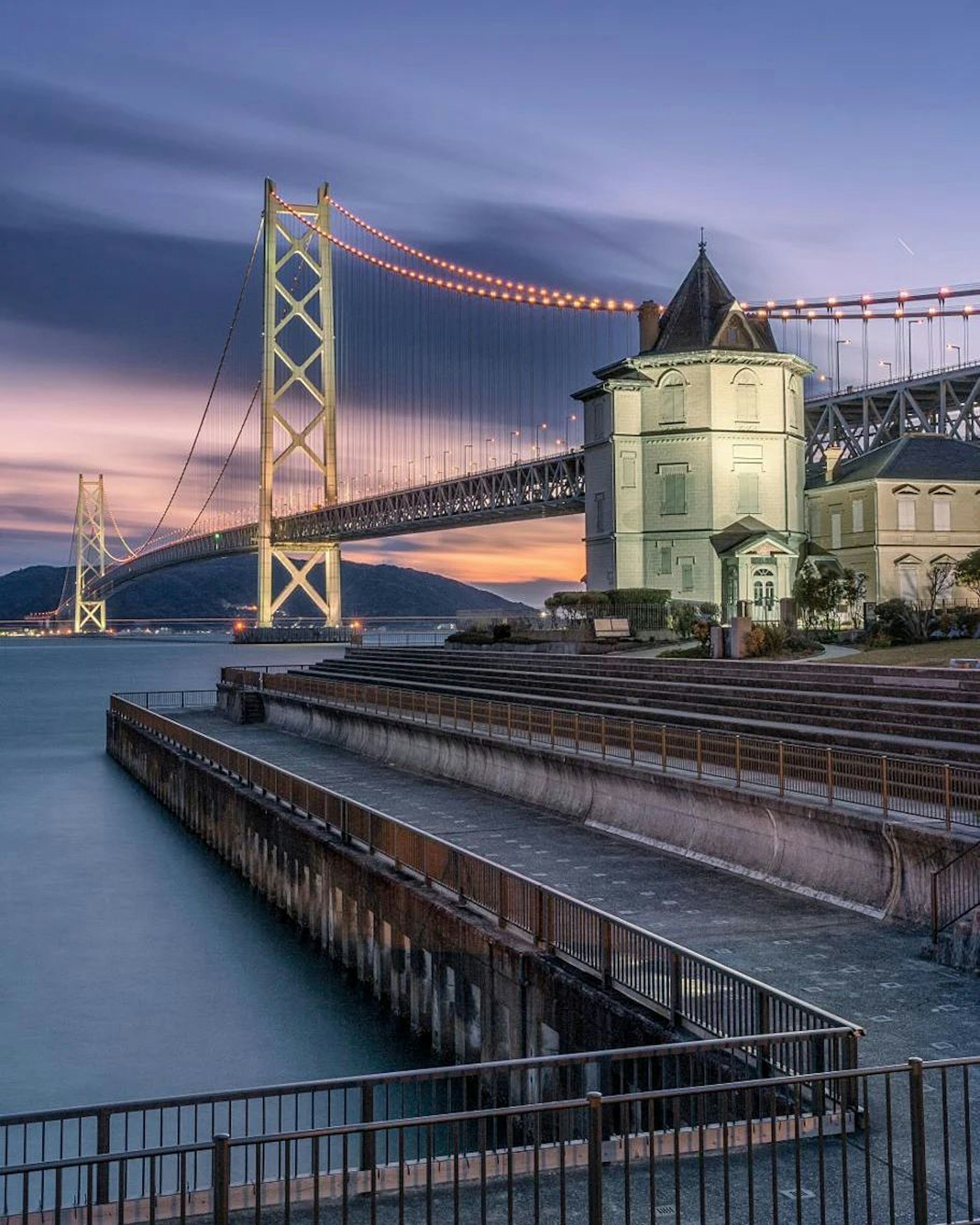 Un magnifique coucher de soleil avec un grand pont et un bâtiment au bord de l'eau