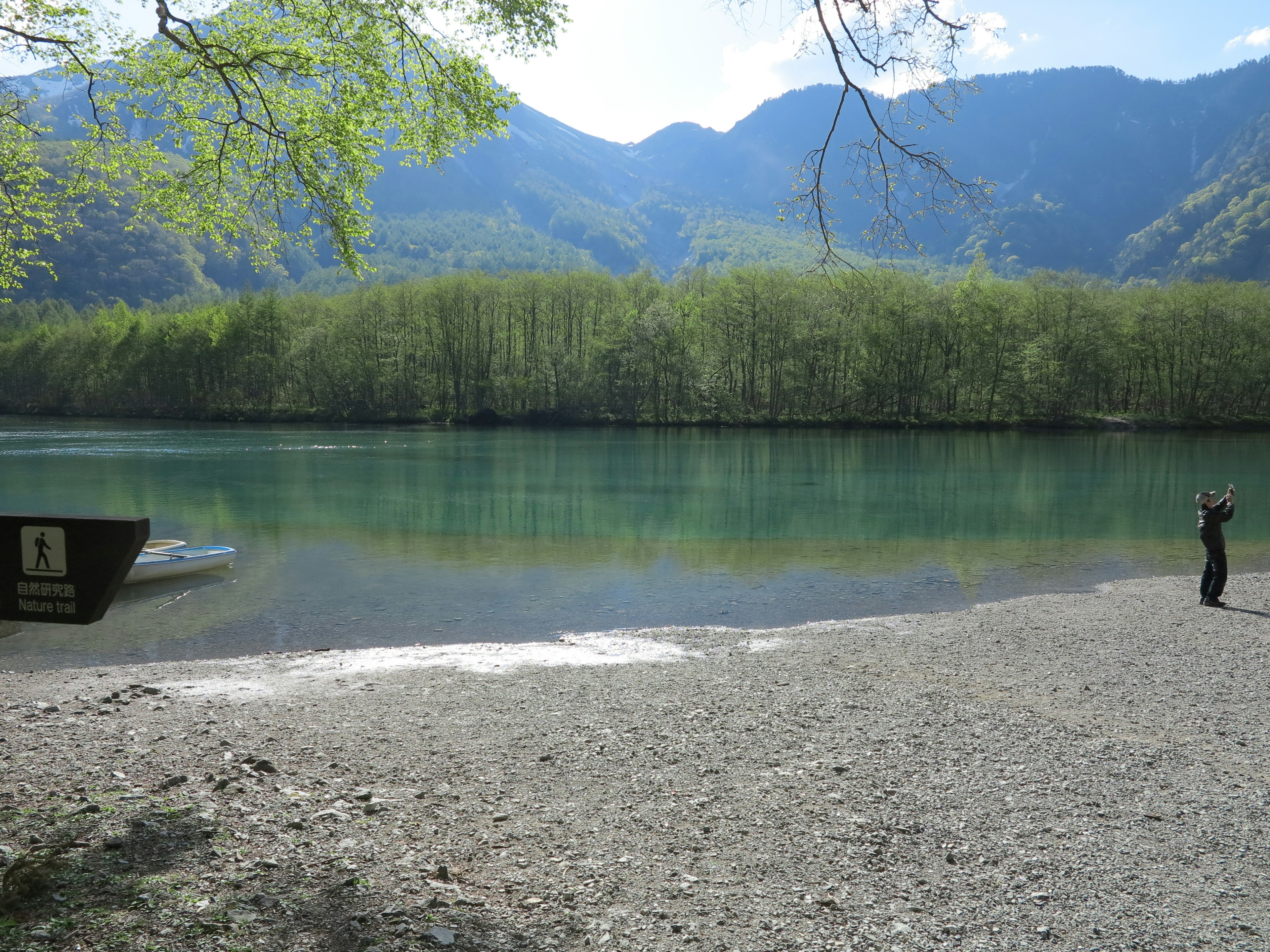 寧靜湖泊與綠色山脈及卵石沙灘的風景