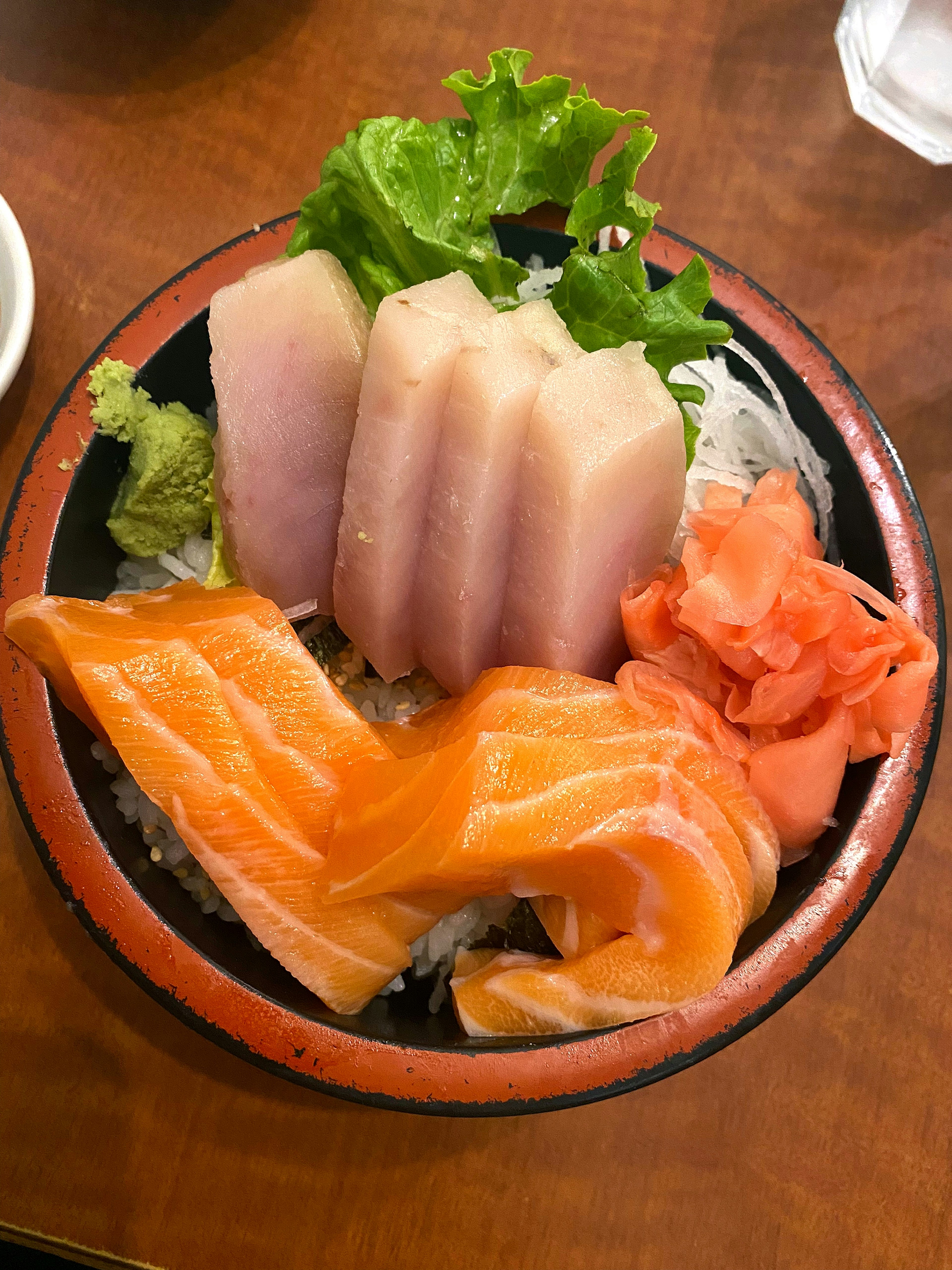 Pilihan sashimi yang berwarna-warni dengan daun salad dalam mangkuk