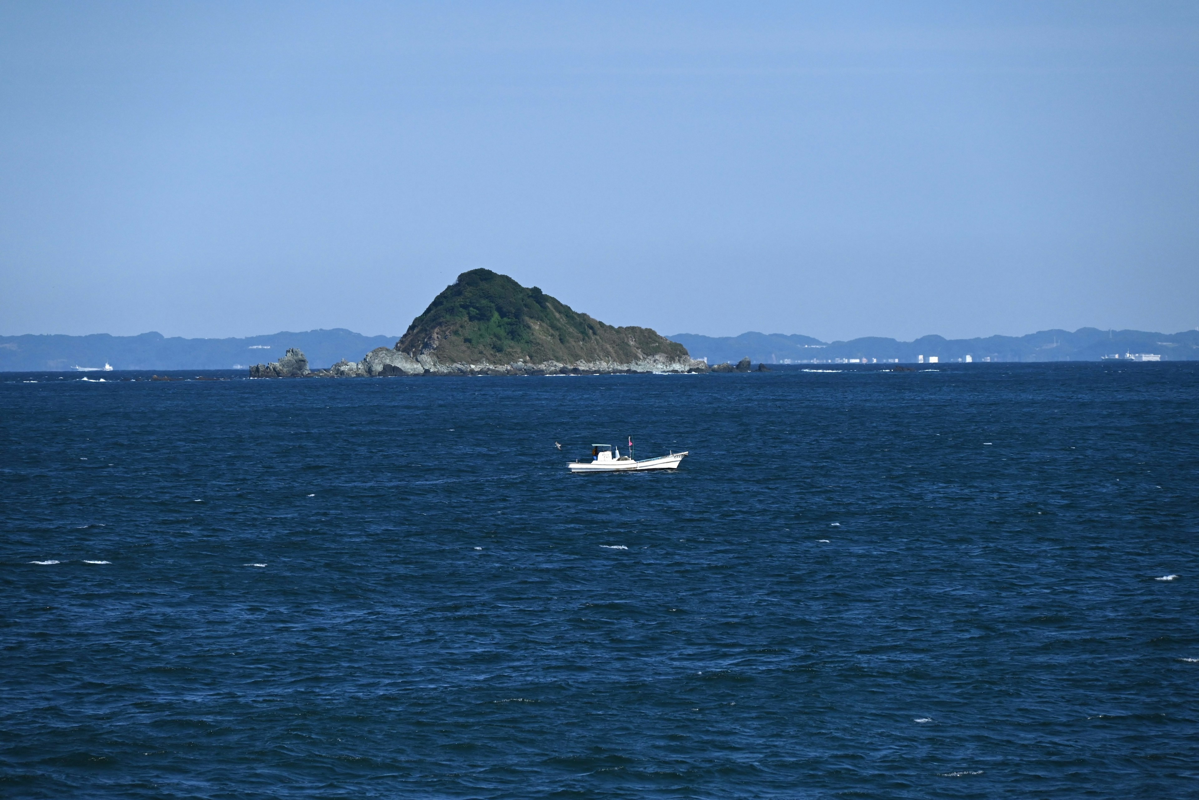 Un petit bateau flottant sur une mer bleue avec une île au loin