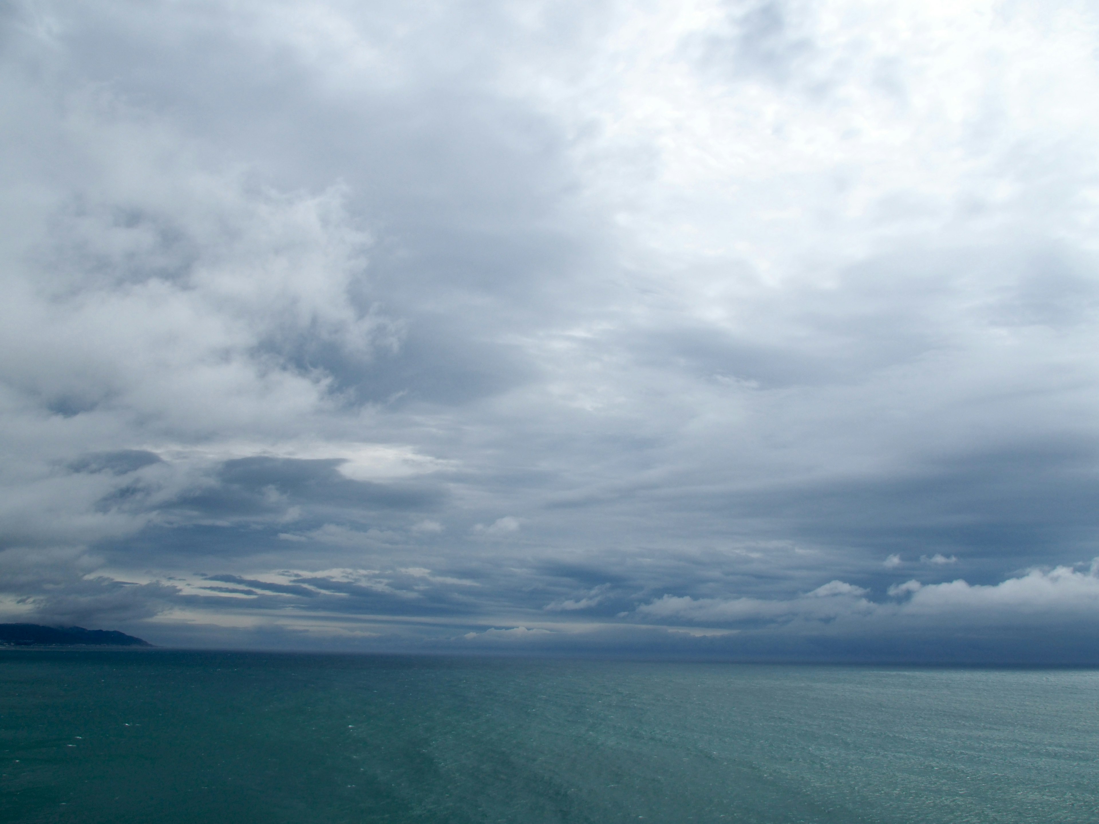 Teal ocean under a cloudy sky