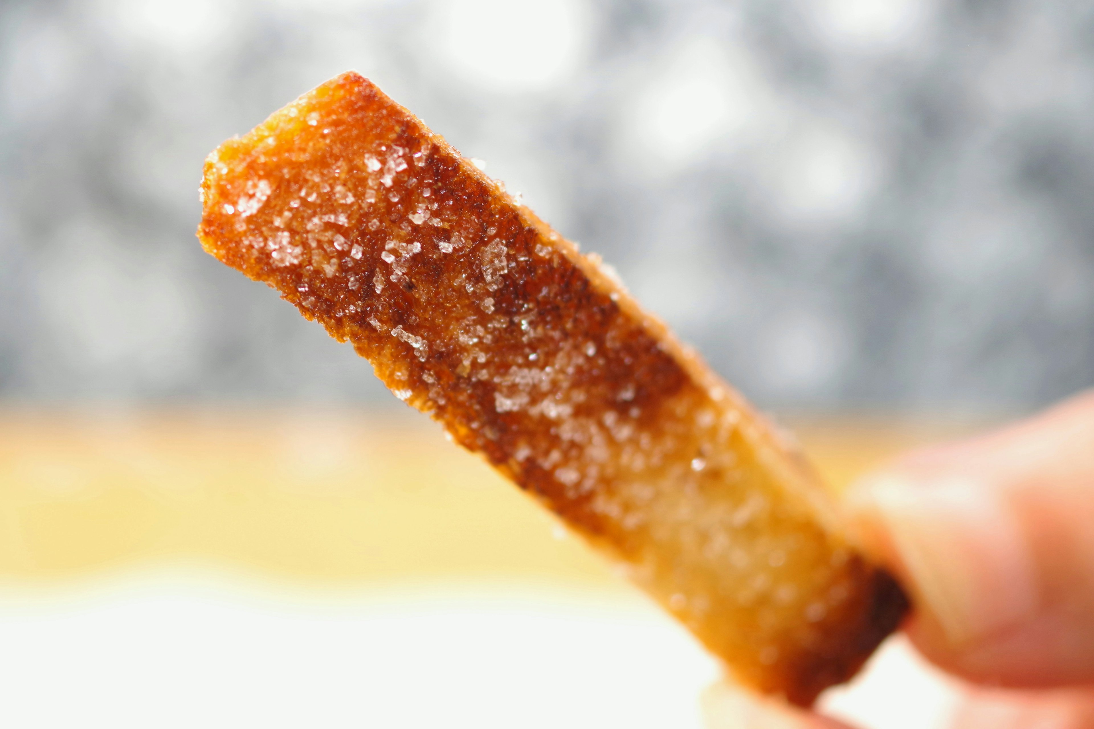 A stick-shaped dessert coated with caramelized sugar and a crispy texture