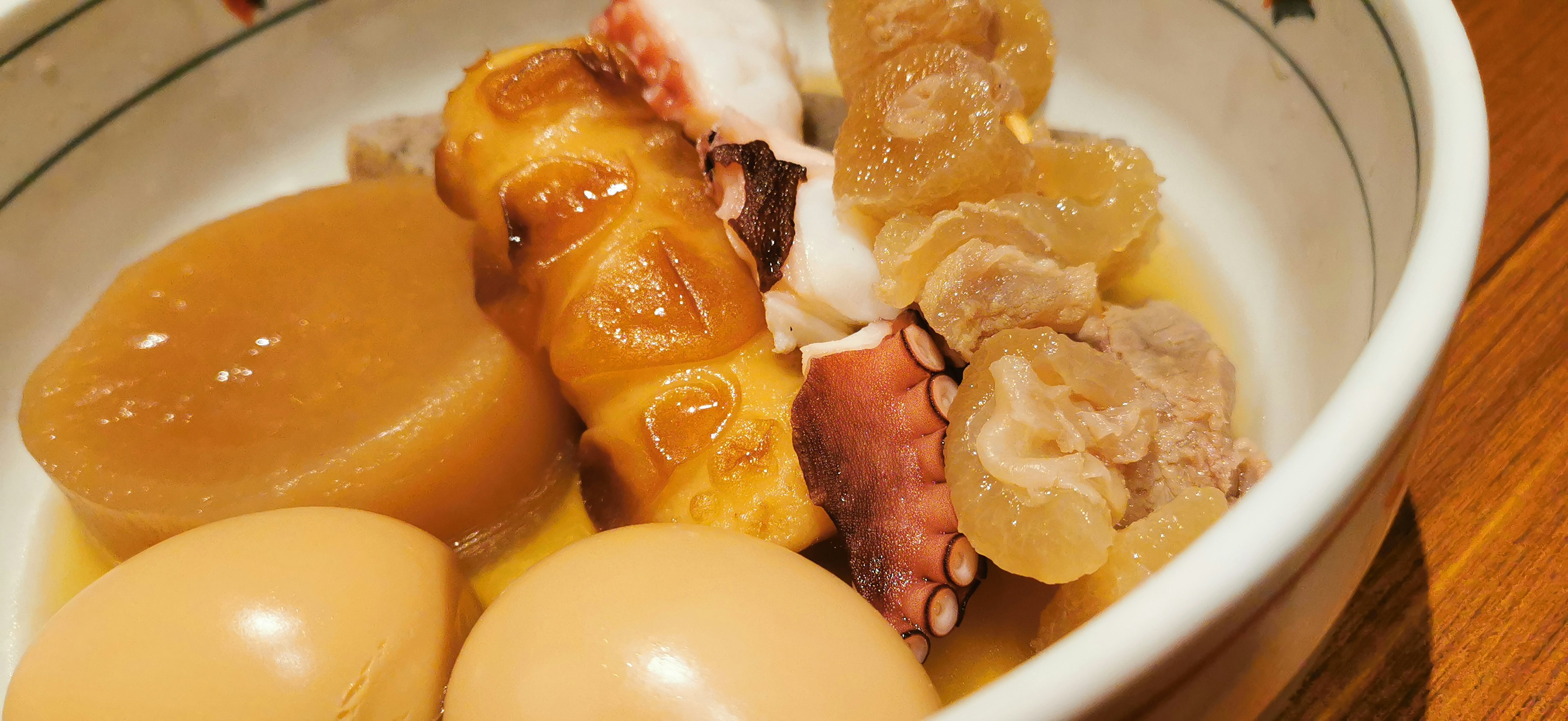 Bowl of warm simmered dish with eggs and octopus legs