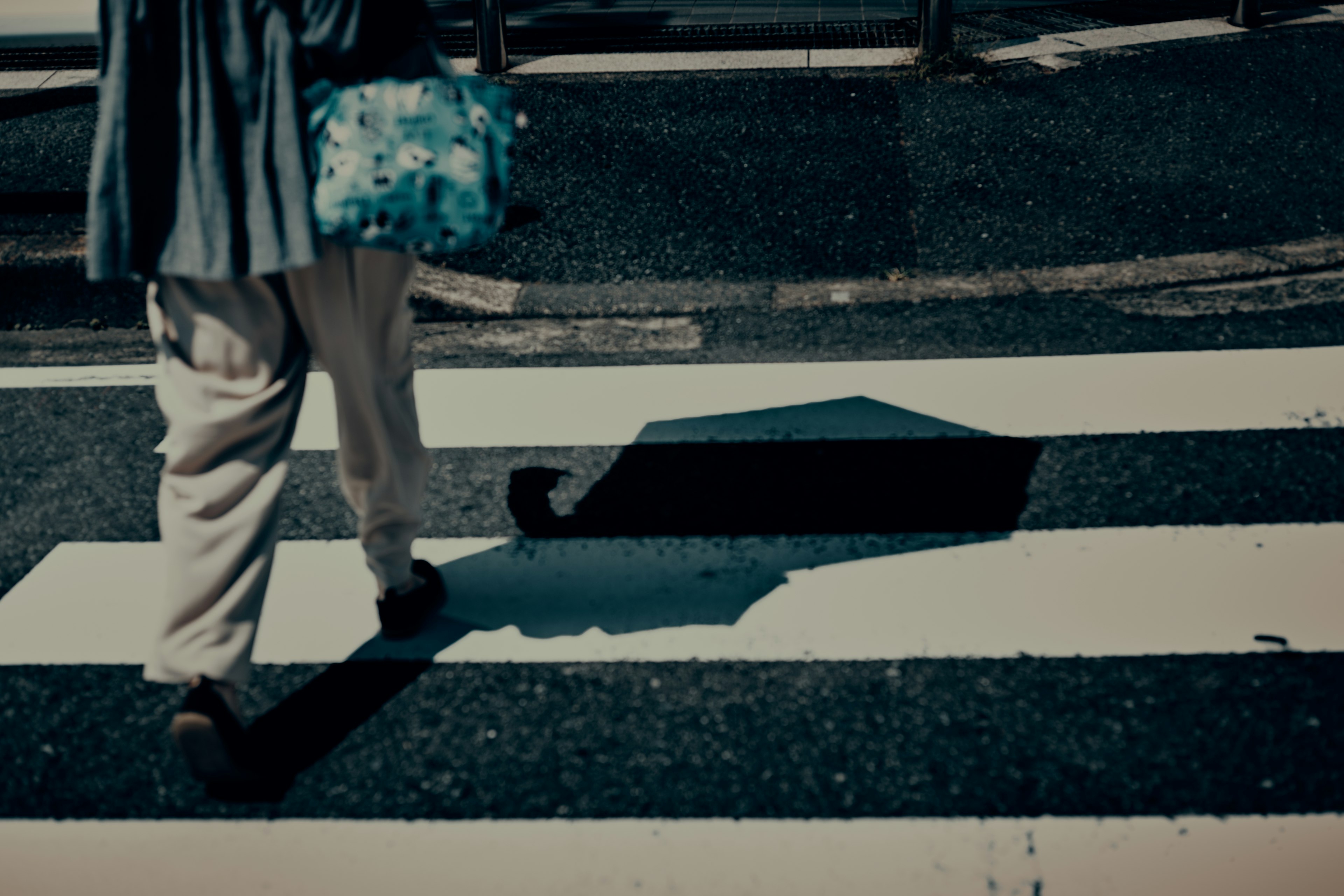 A person's feet and shadow crossing a zebra cross