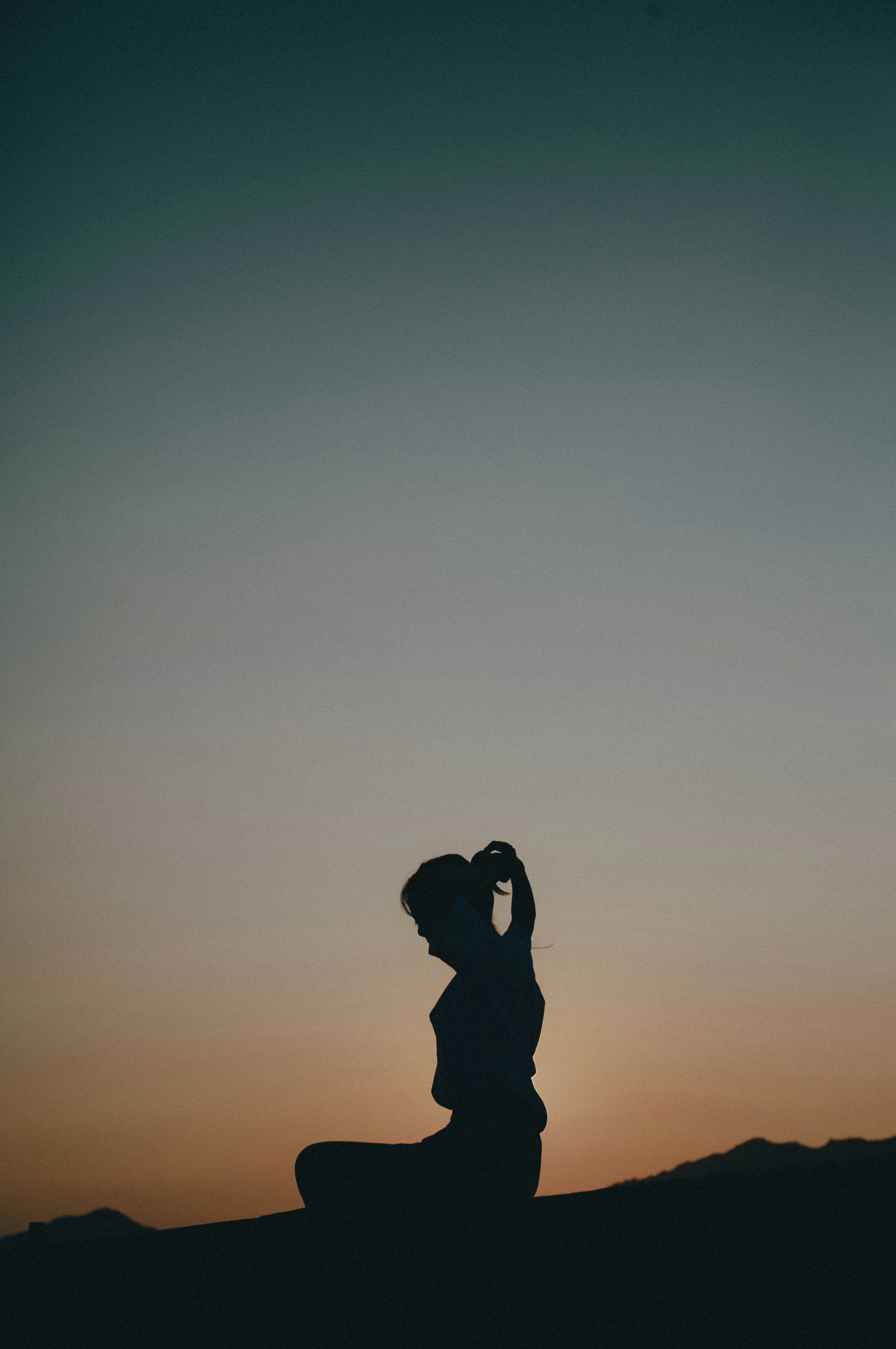 Silhouette of a woman sitting against a sunset