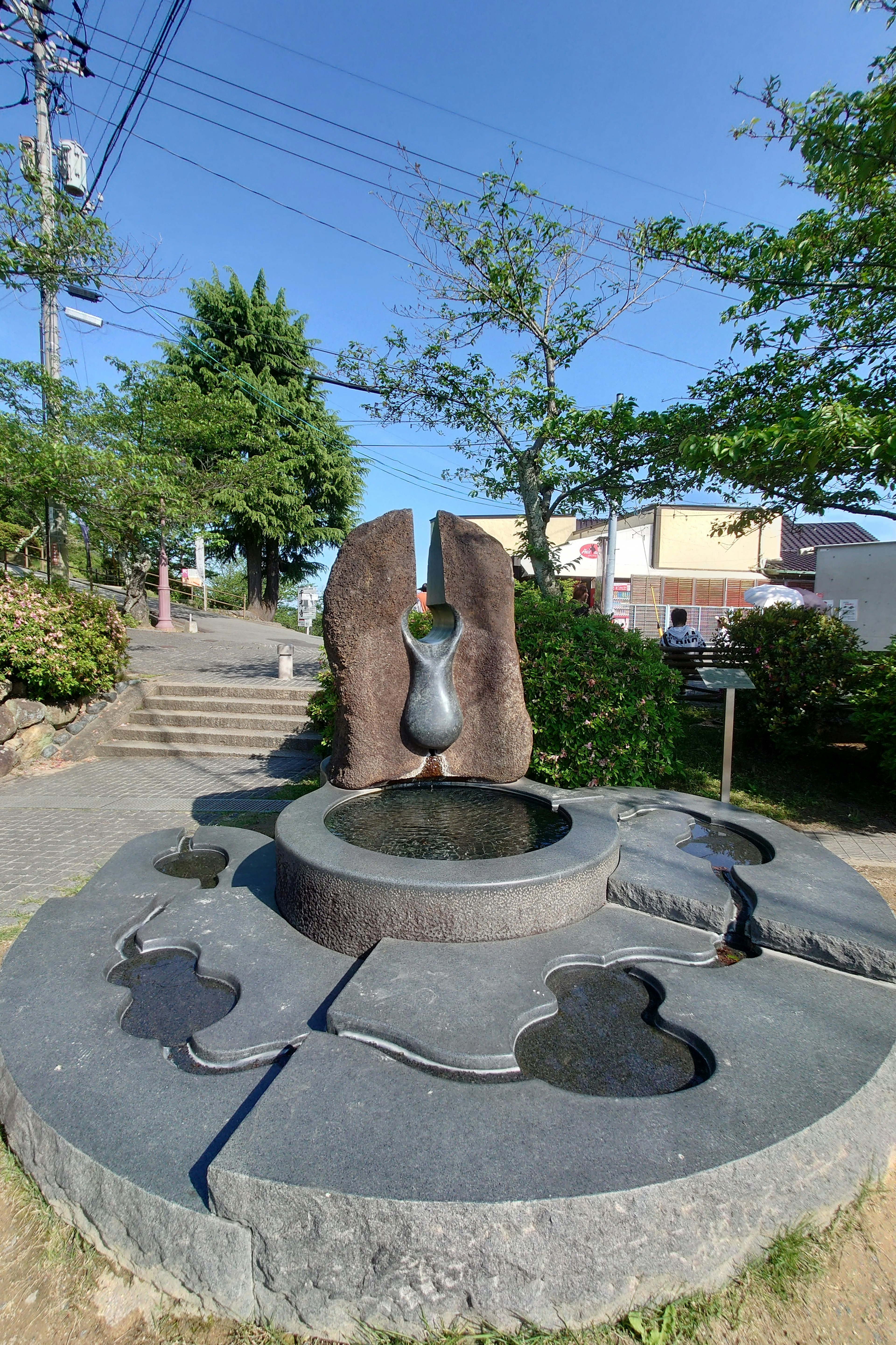 Einzigartiger Steinbrunnen in einem Park umgeben von Grün