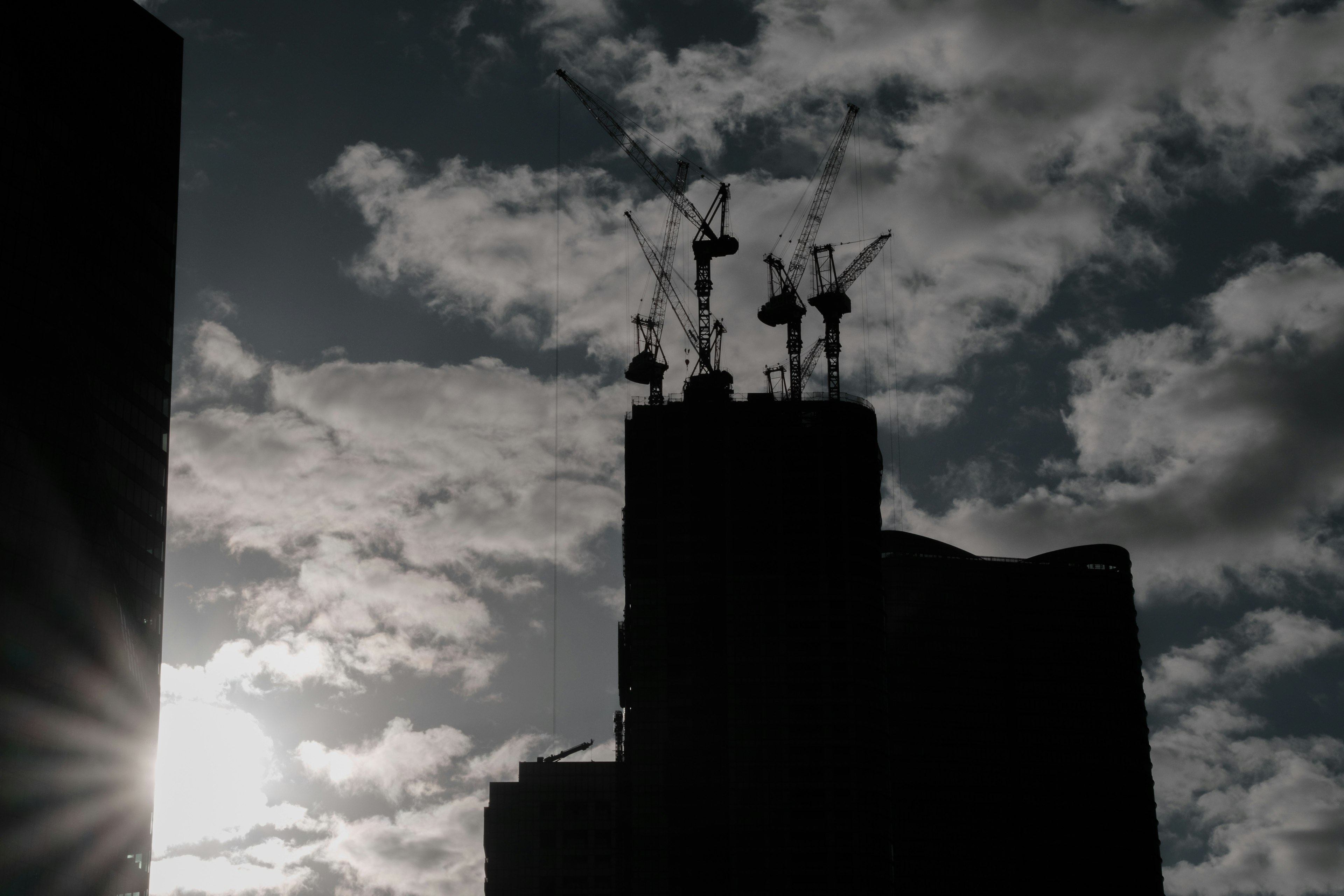 Edificios y grúas en silueta contra un cielo de atardecer