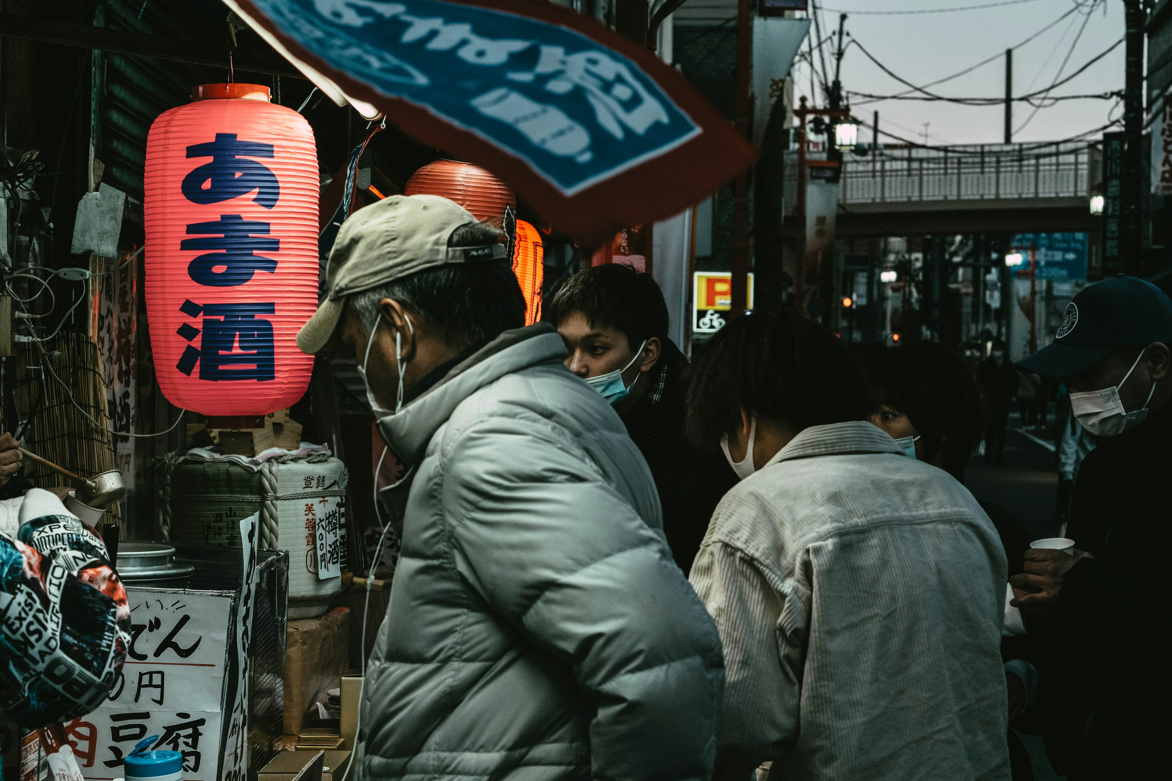 人們聚集在一個食品攤位前的夜間街景，顯眼的紅色燈籠