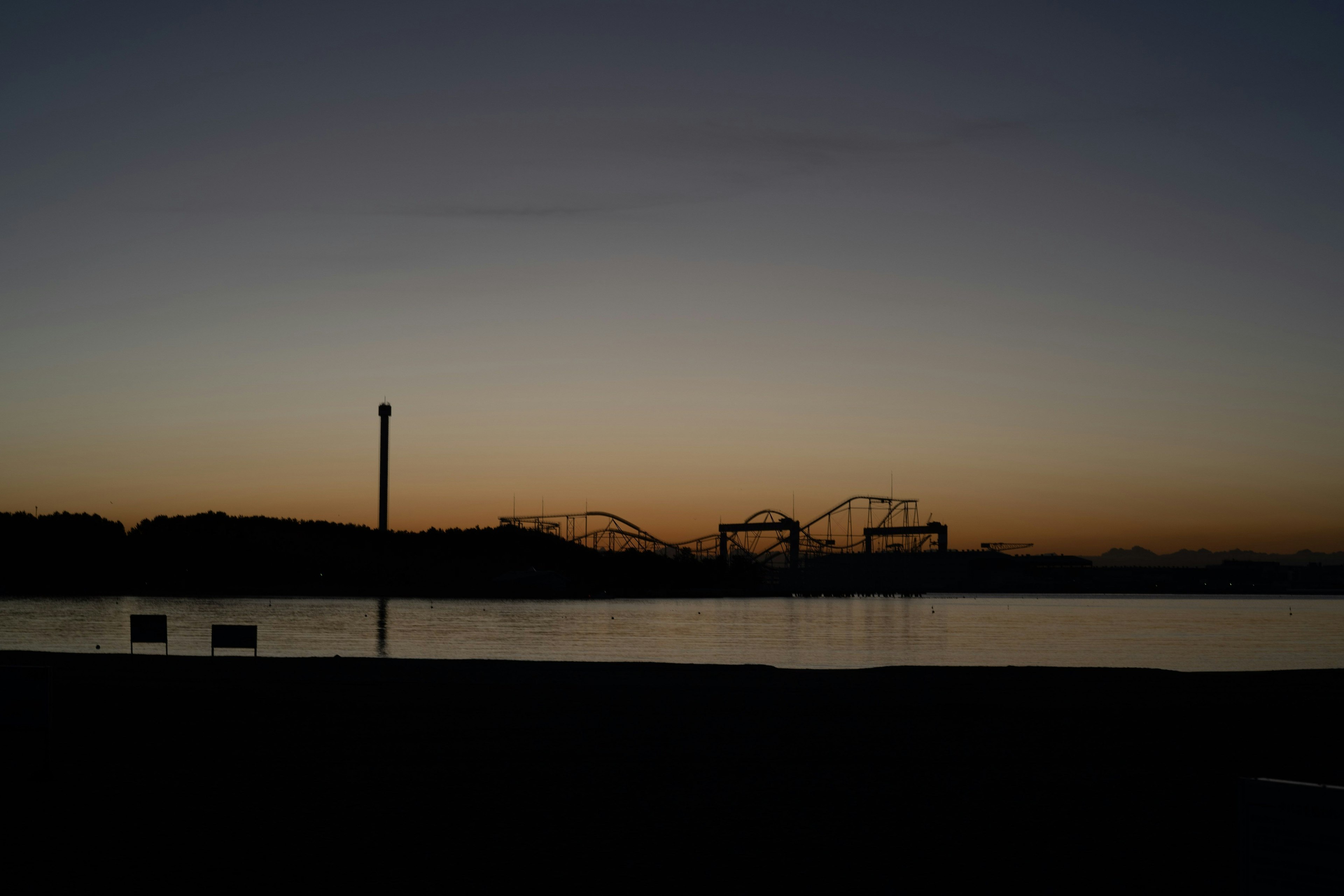 夕暮れ時の海岸線に沿った遊園地のシルエット
