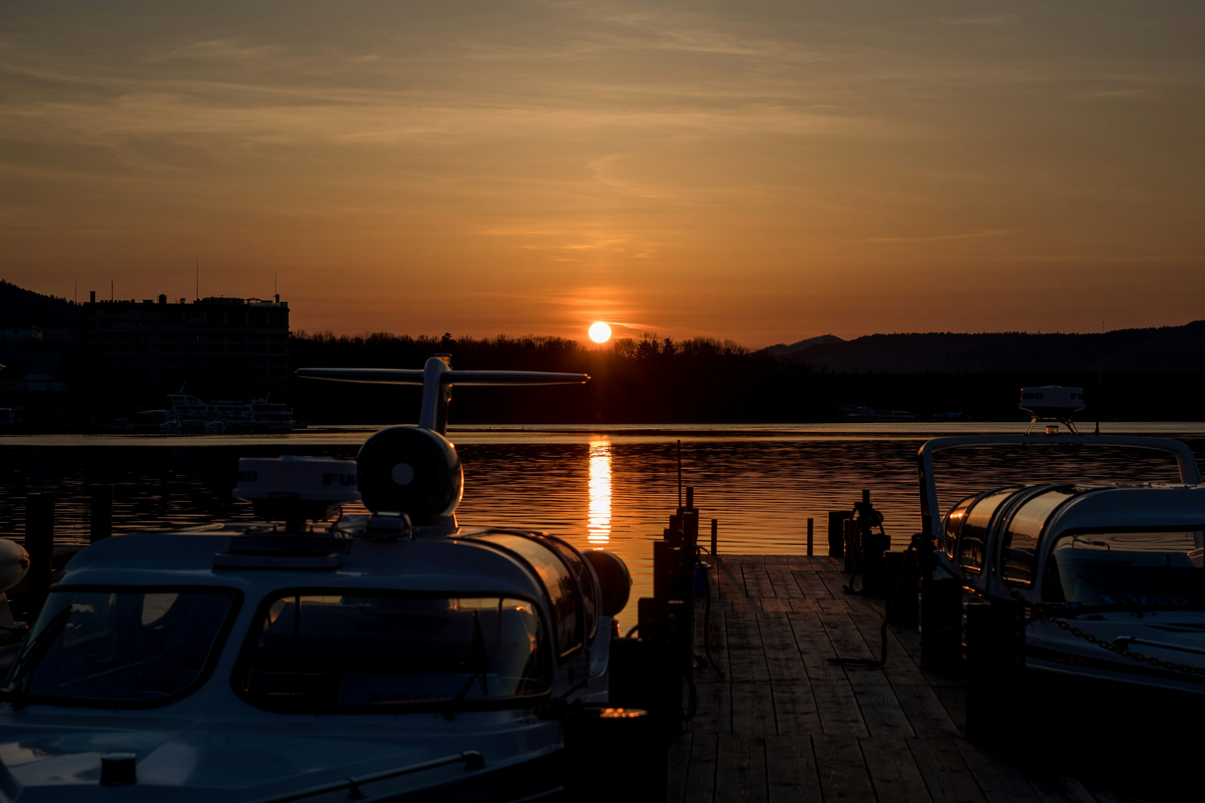 Tramonto che si riflette sull'acqua in un porto con barche allineate sul molo