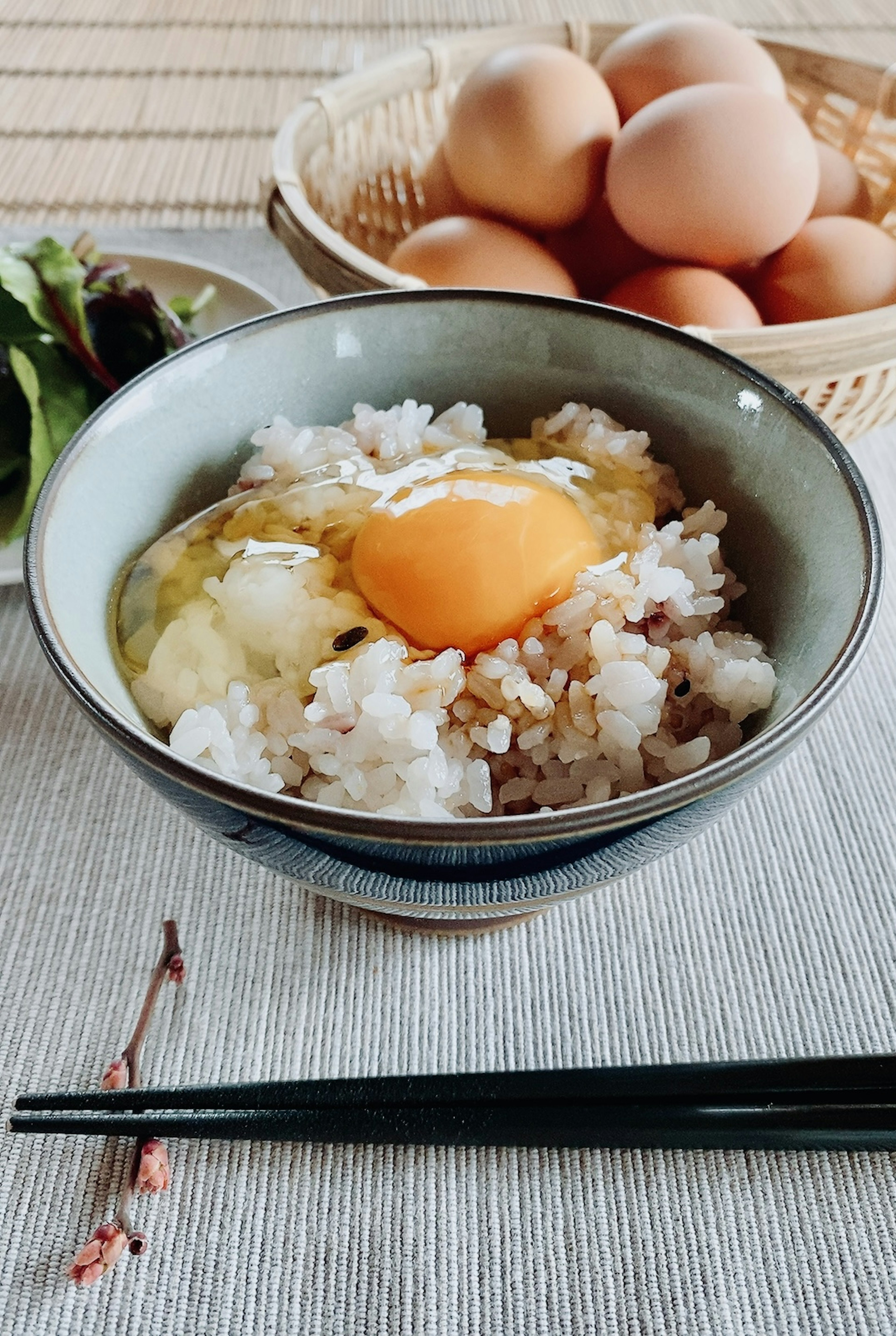 Bol de riz surmonté d'un œuf cru et un panier d'œufs