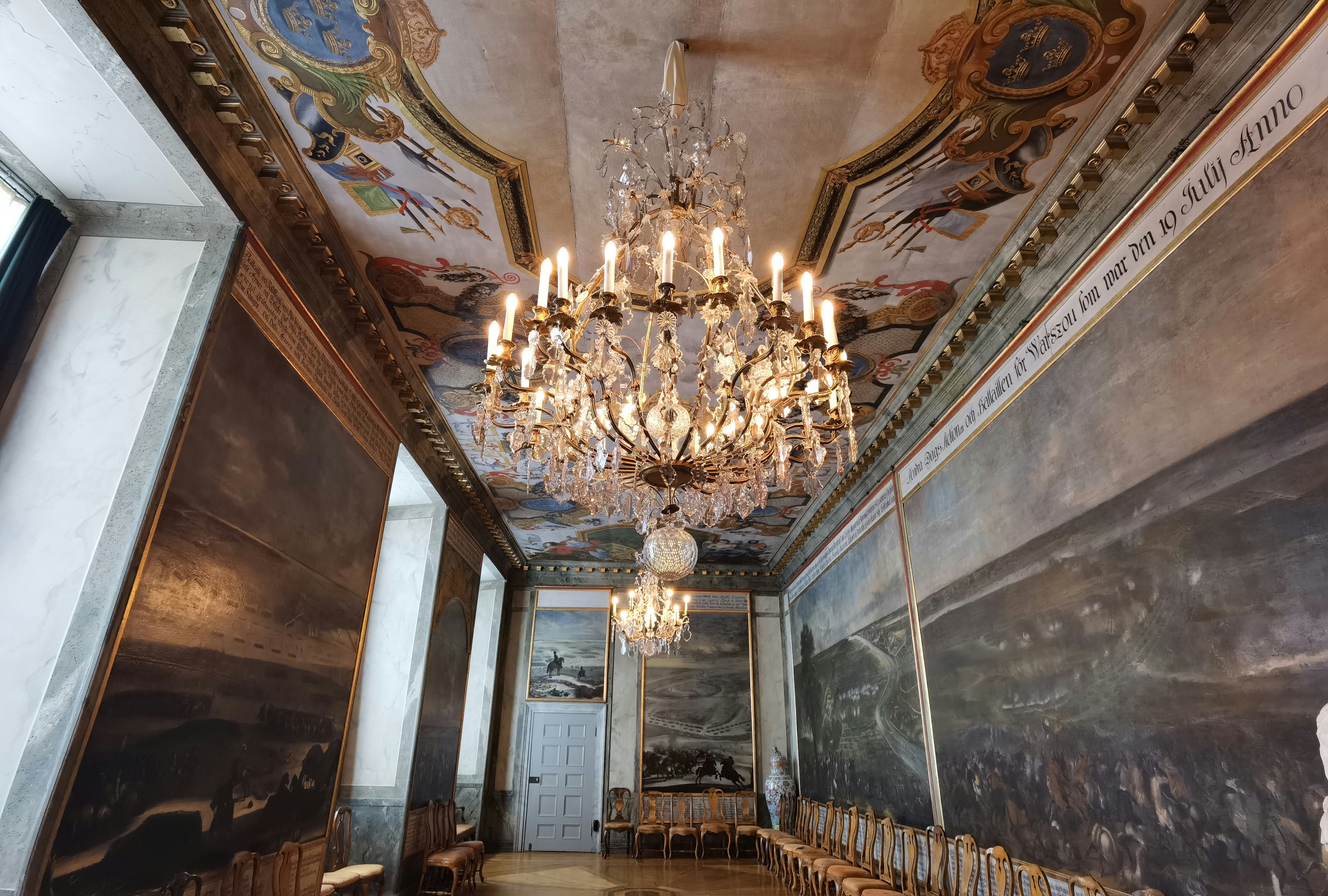 Spacious room with a luxurious chandelier and grand paintings on the walls