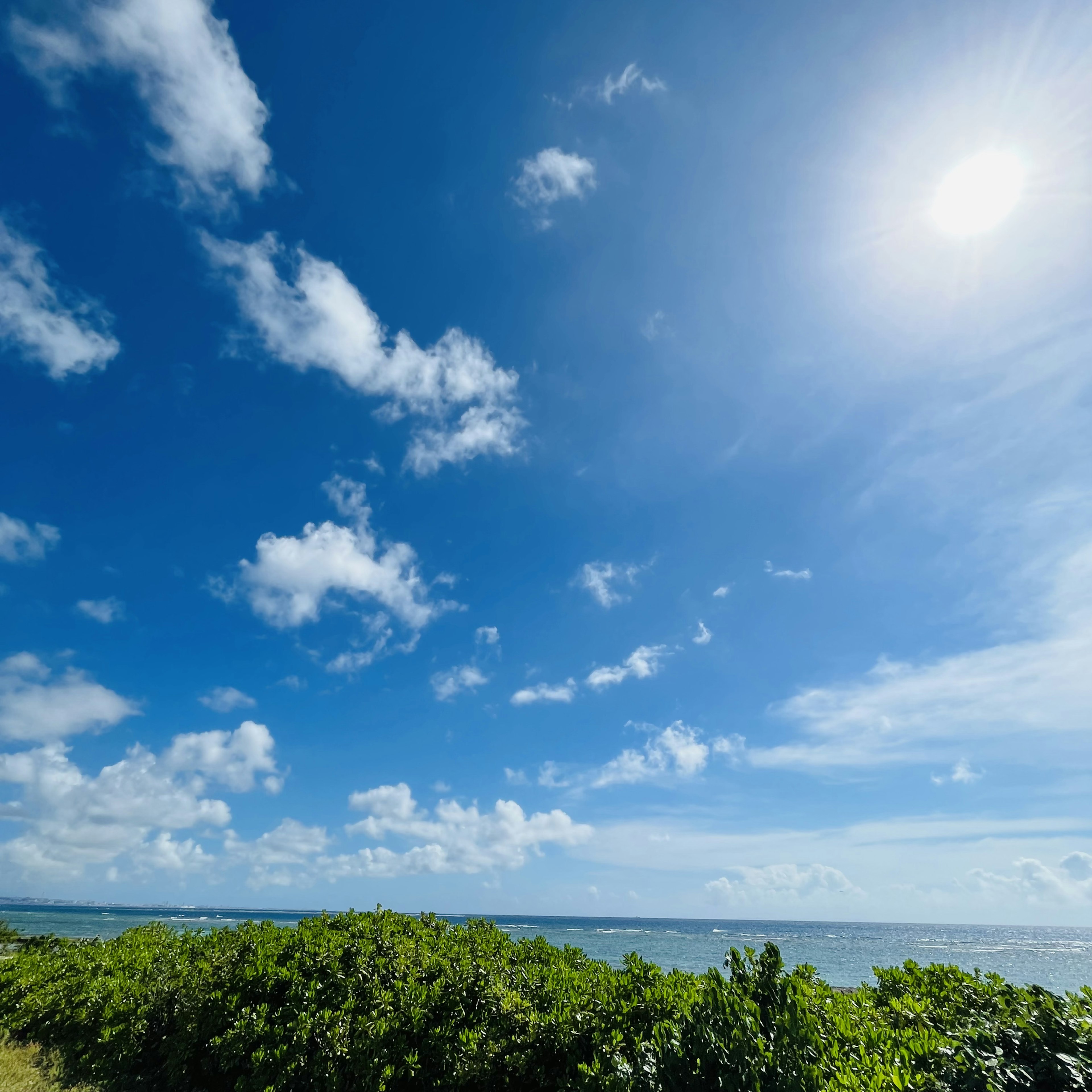 青い空と白い雲が広がる海辺の風景 太陽が輝いている