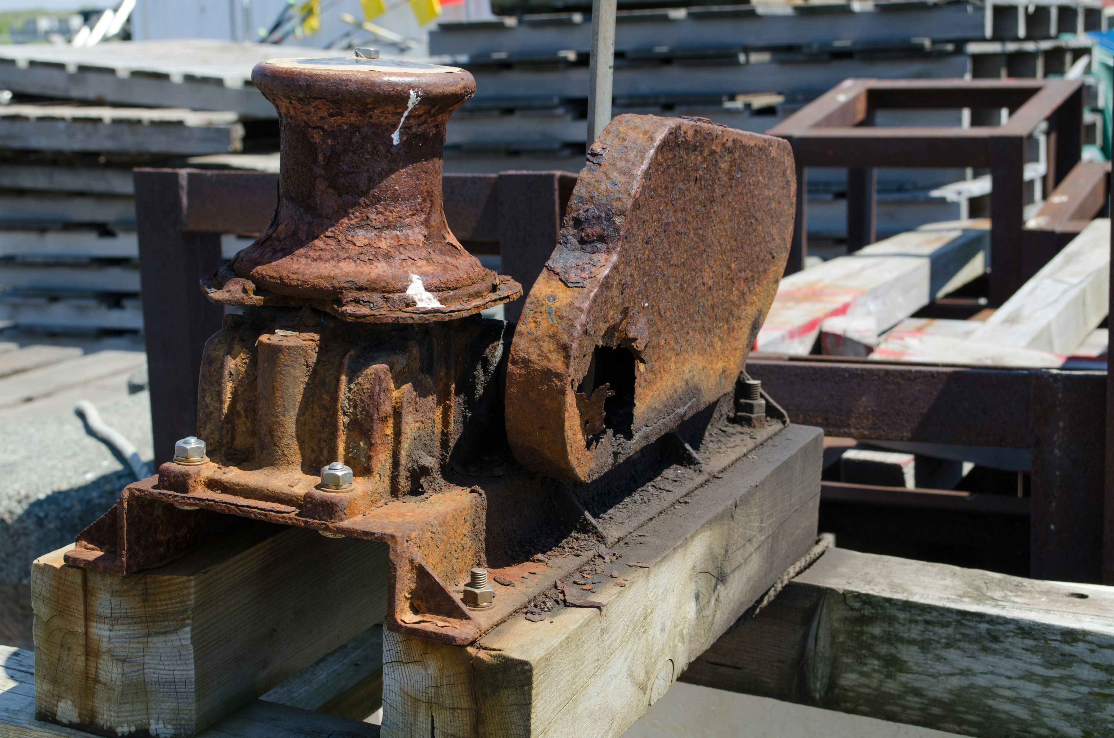 古い鉄製の機械部品が木製の基台に置かれている rusted iron machinery part on wooden base