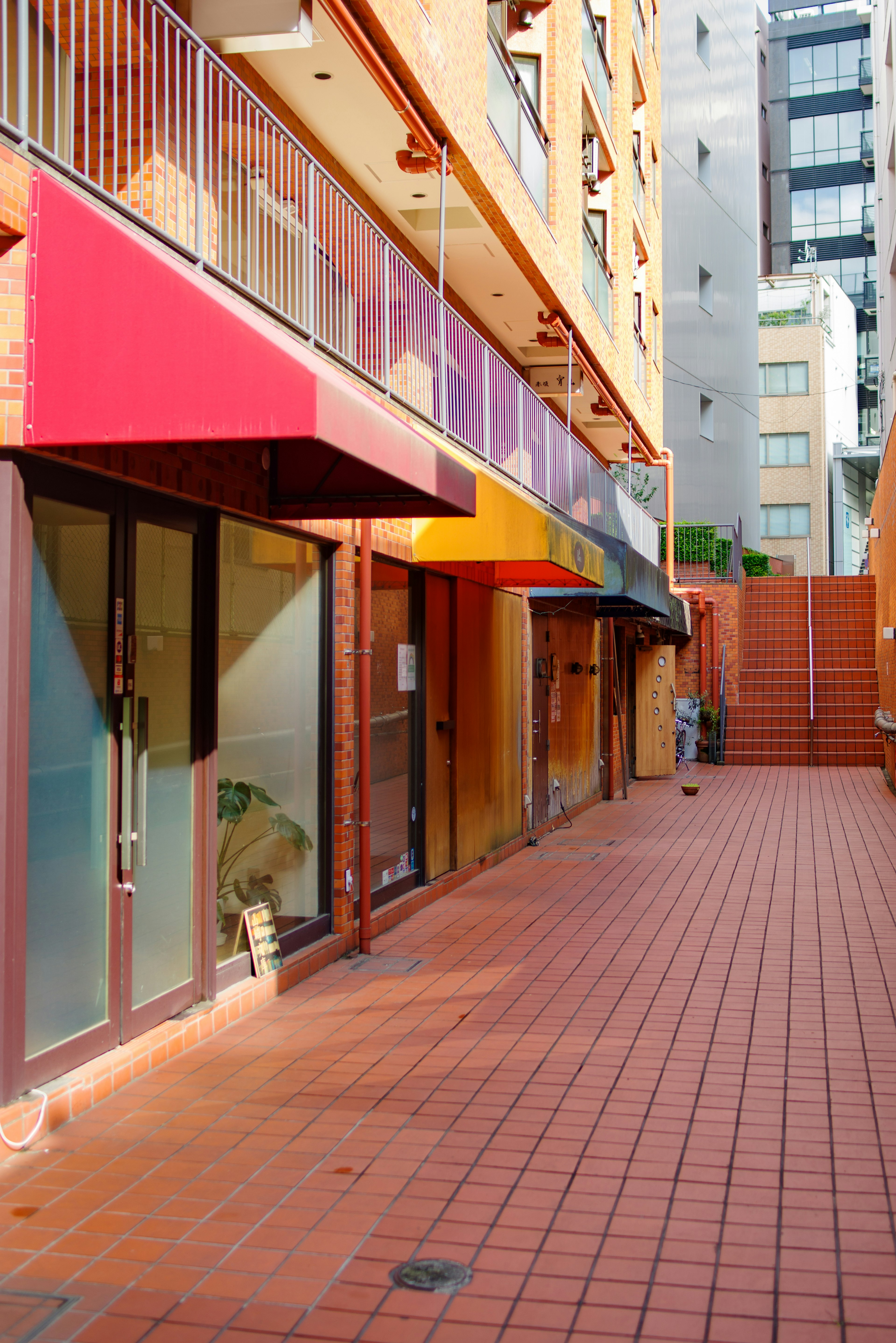 Commercial building exterior with red awnings and tiled walkway