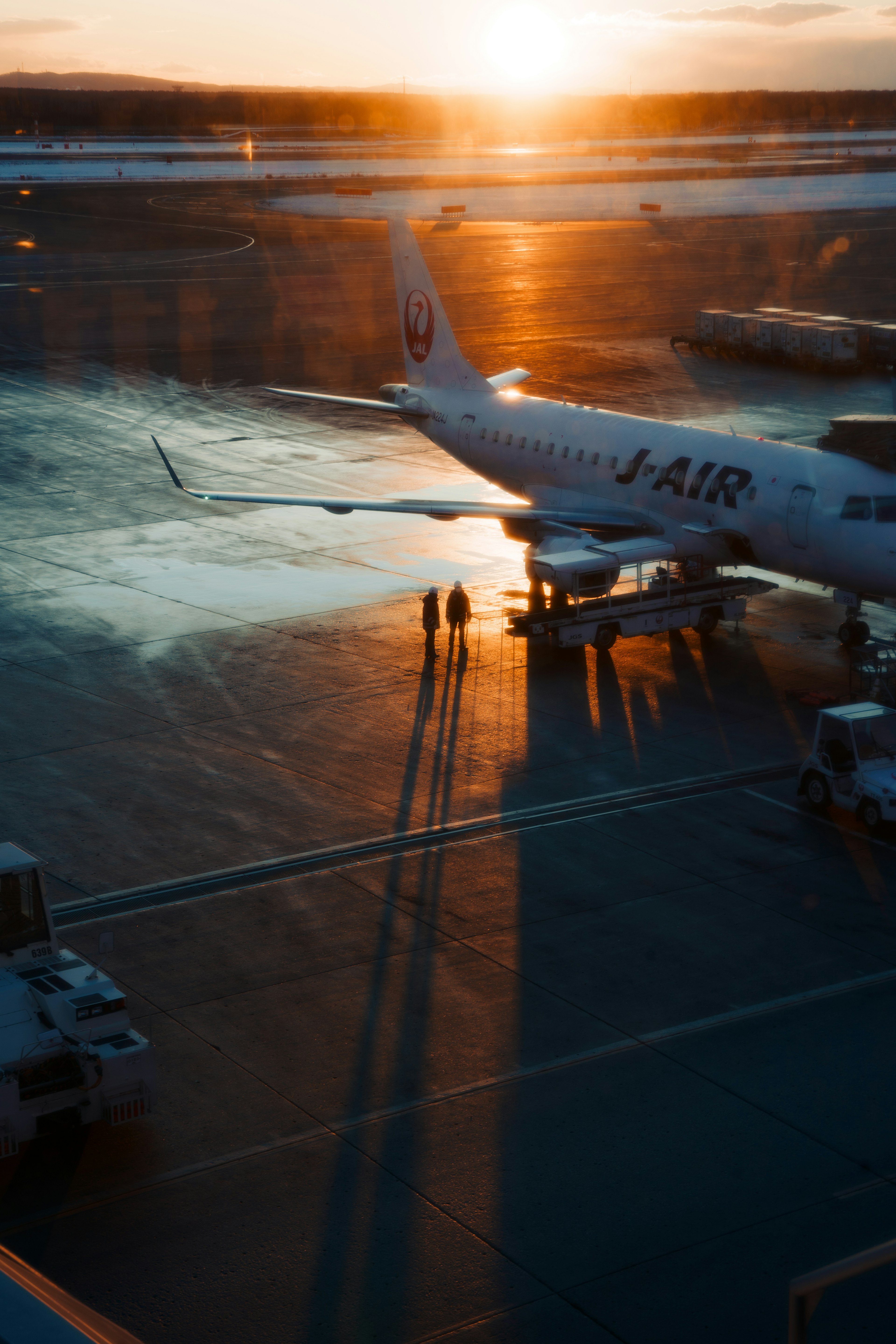 夕日を背景にした空港の滑走路に停まる飛行機とその影