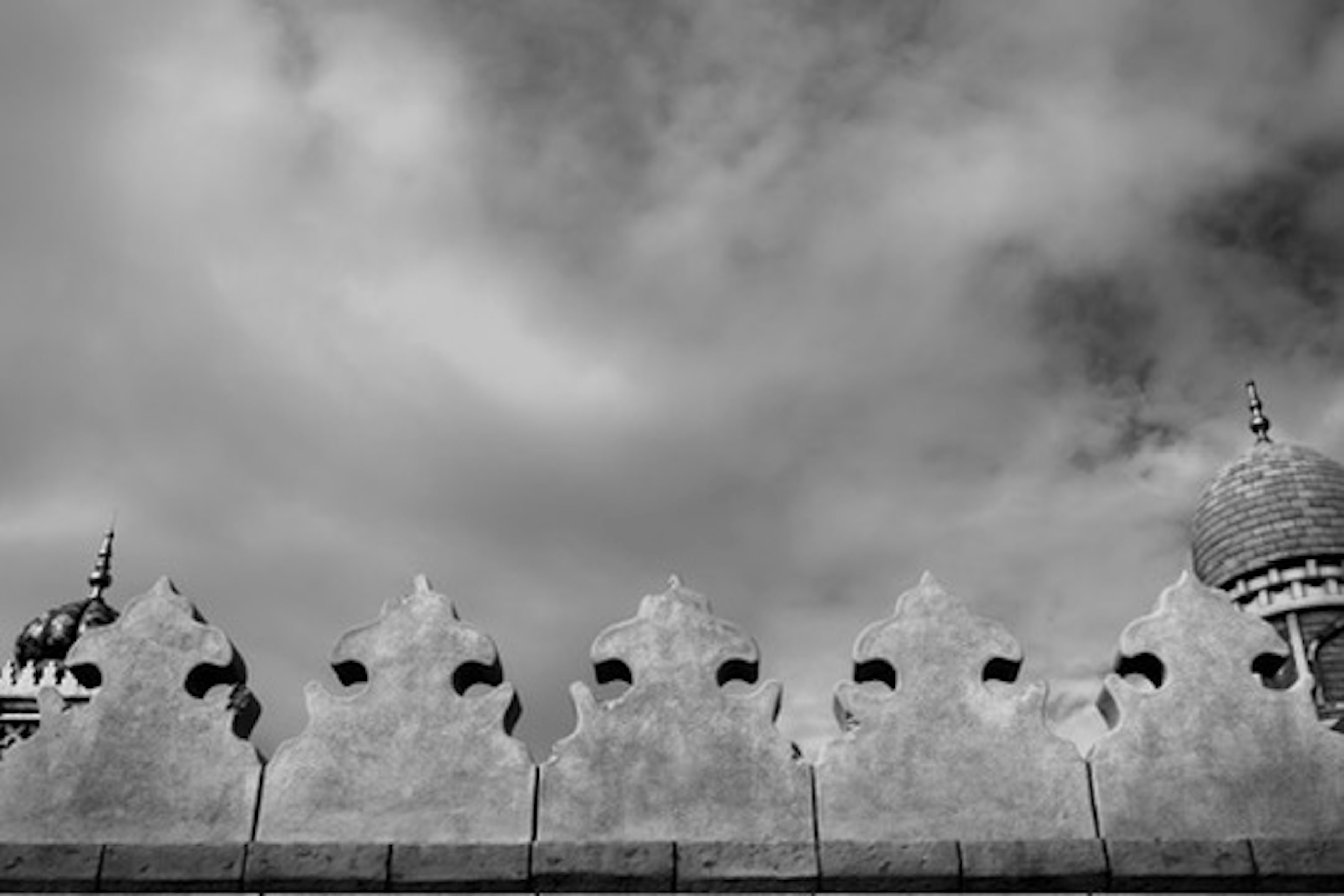 Image présentant le sommet décoratif d'un mur contre un ciel noir et blanc