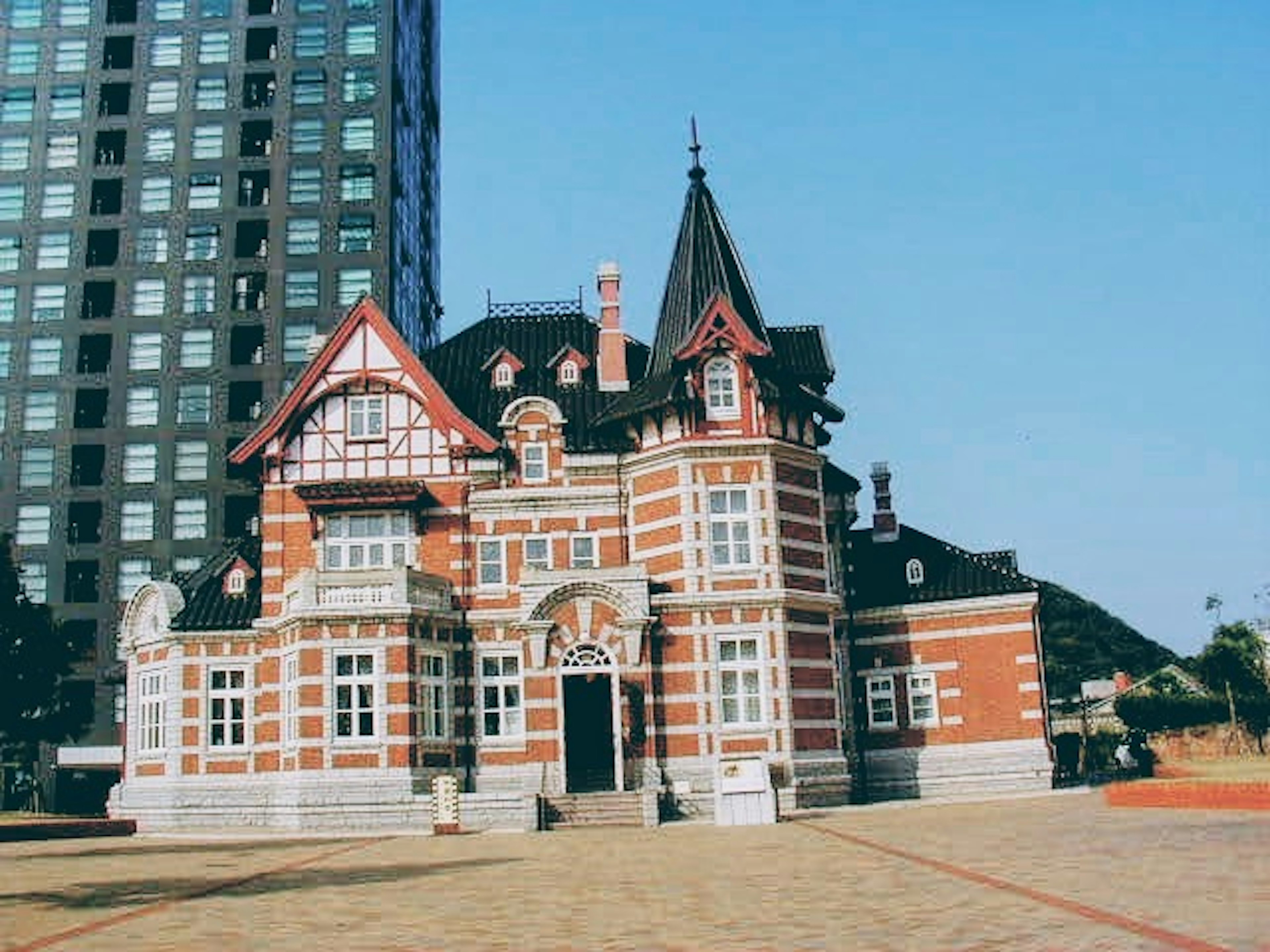 Bâtiment en briques rouges traditionnelles contrastant avec un gratte-ciel moderne