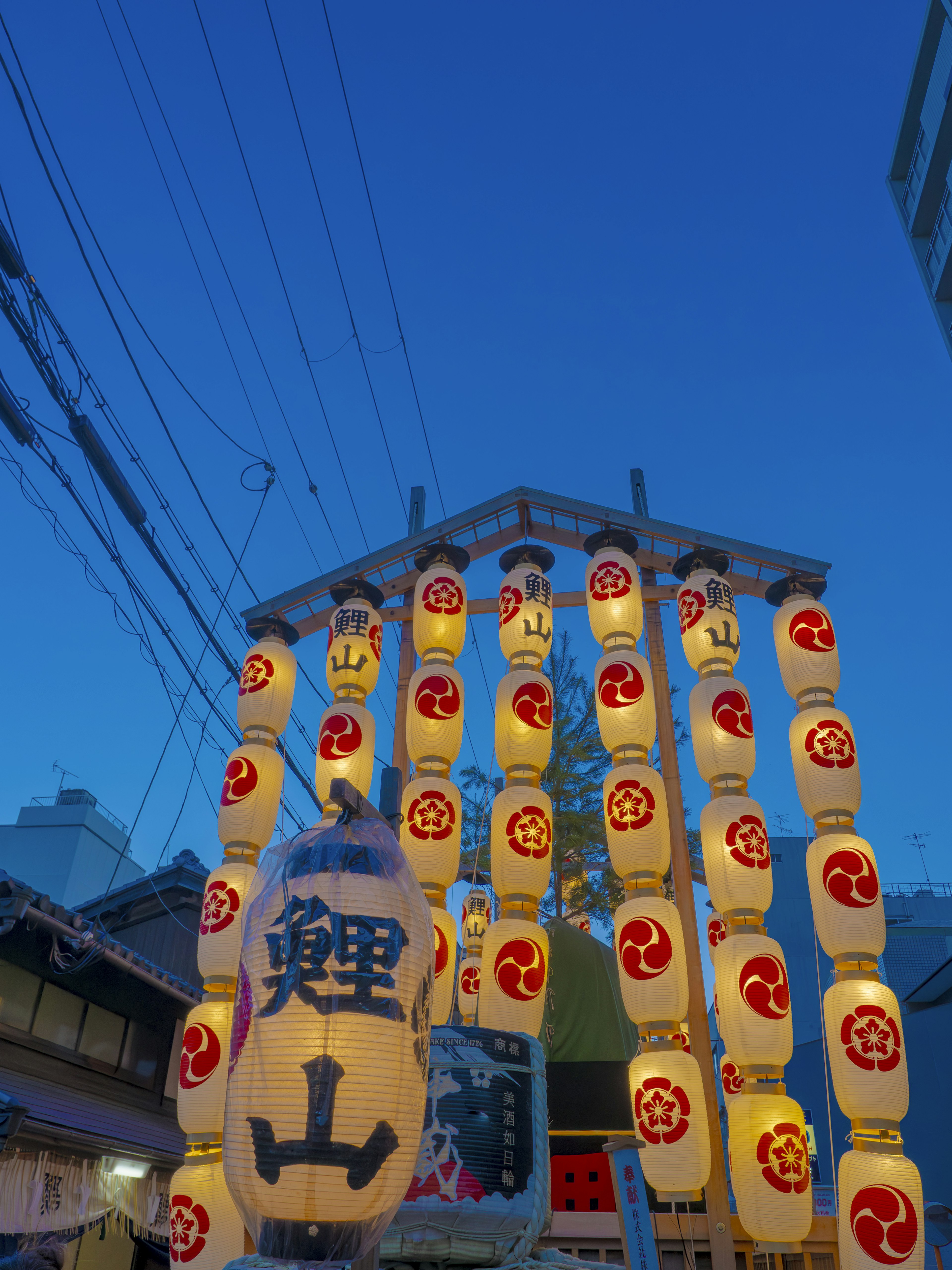 Festival scene with multiple lanterns and a large lantern under a blue sky