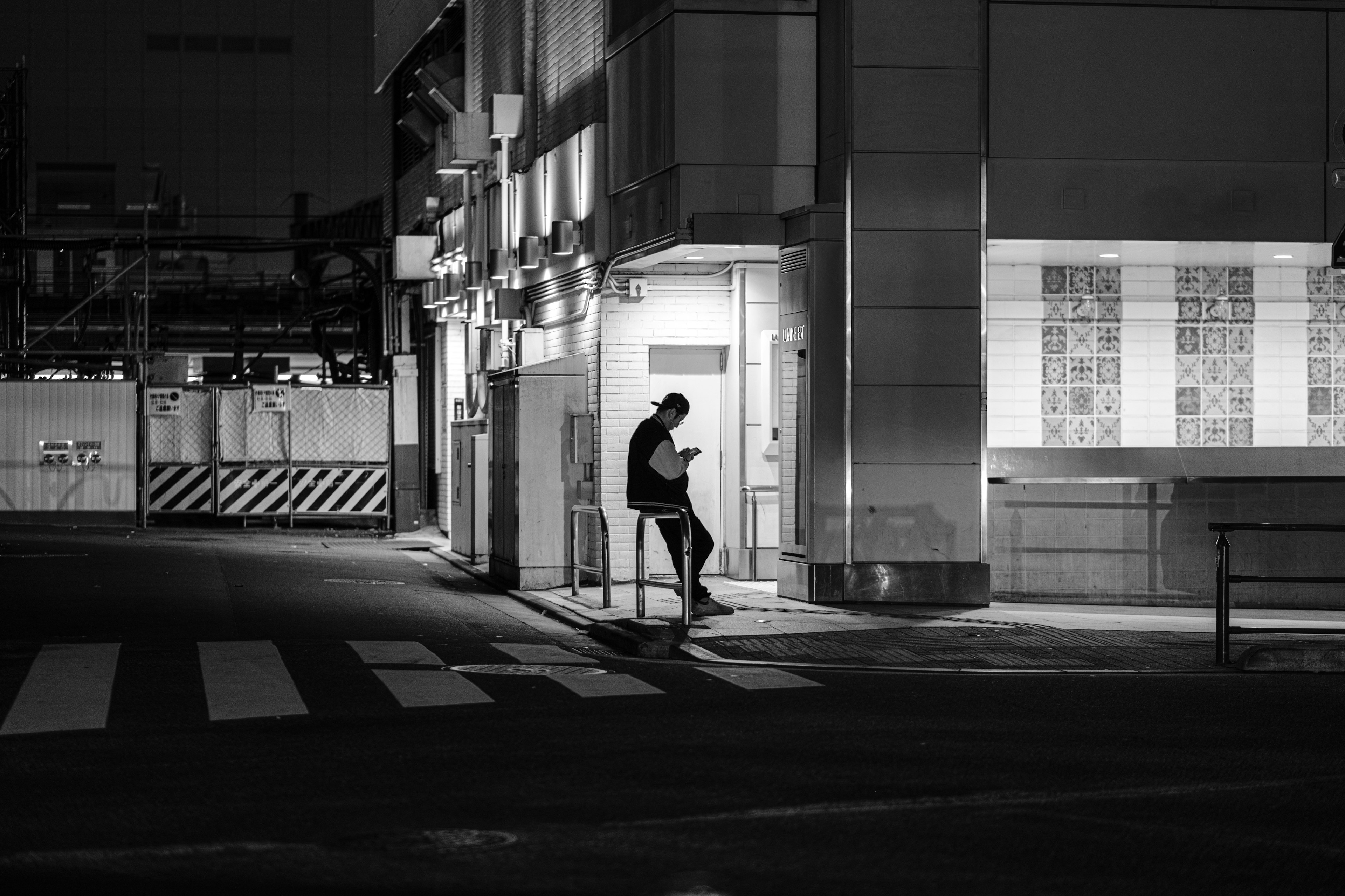 夜の街角に立つ人物と明るい建物のコントラスト