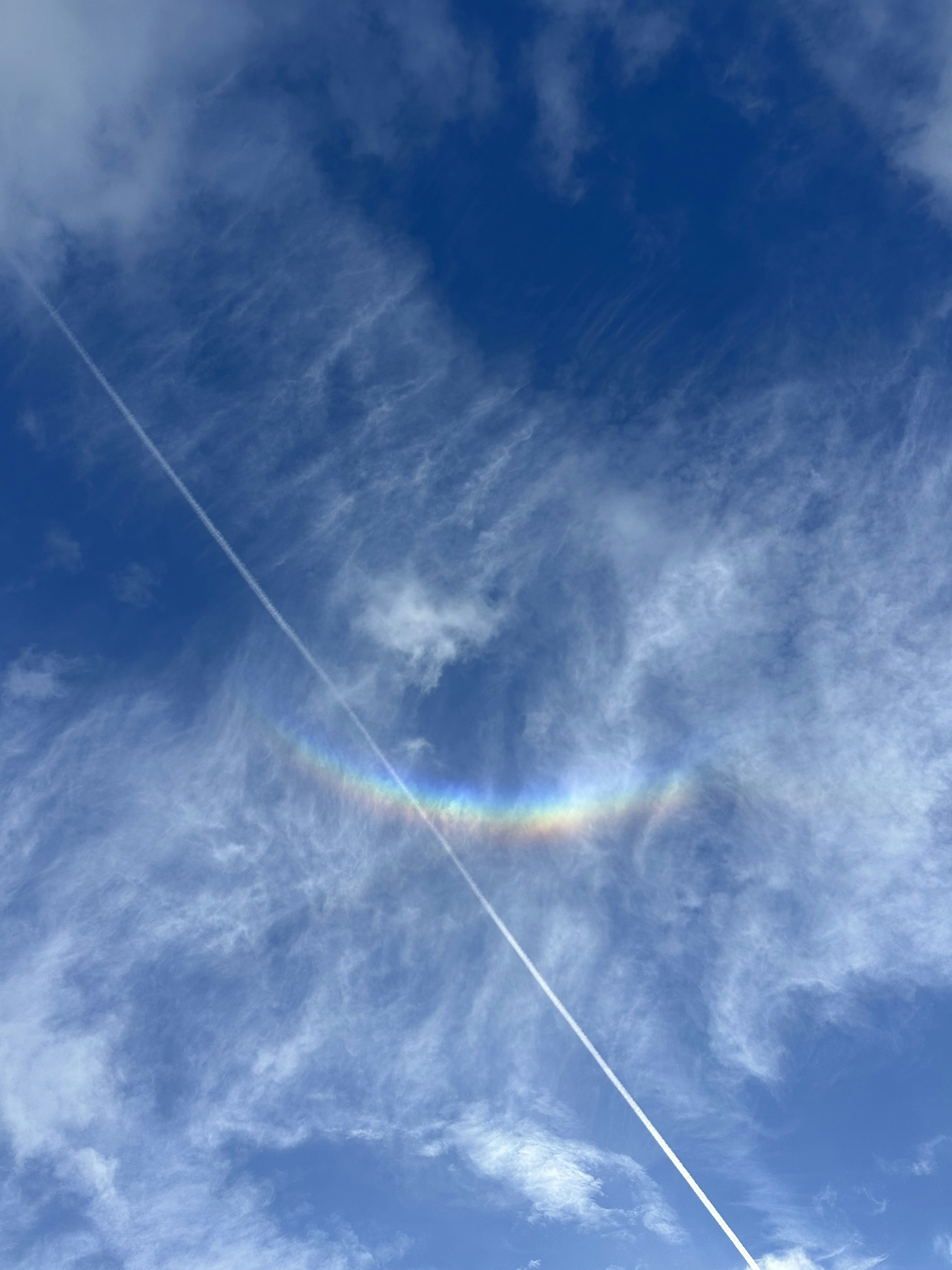 Blue sky with wispy clouds and a rainbow-like arc