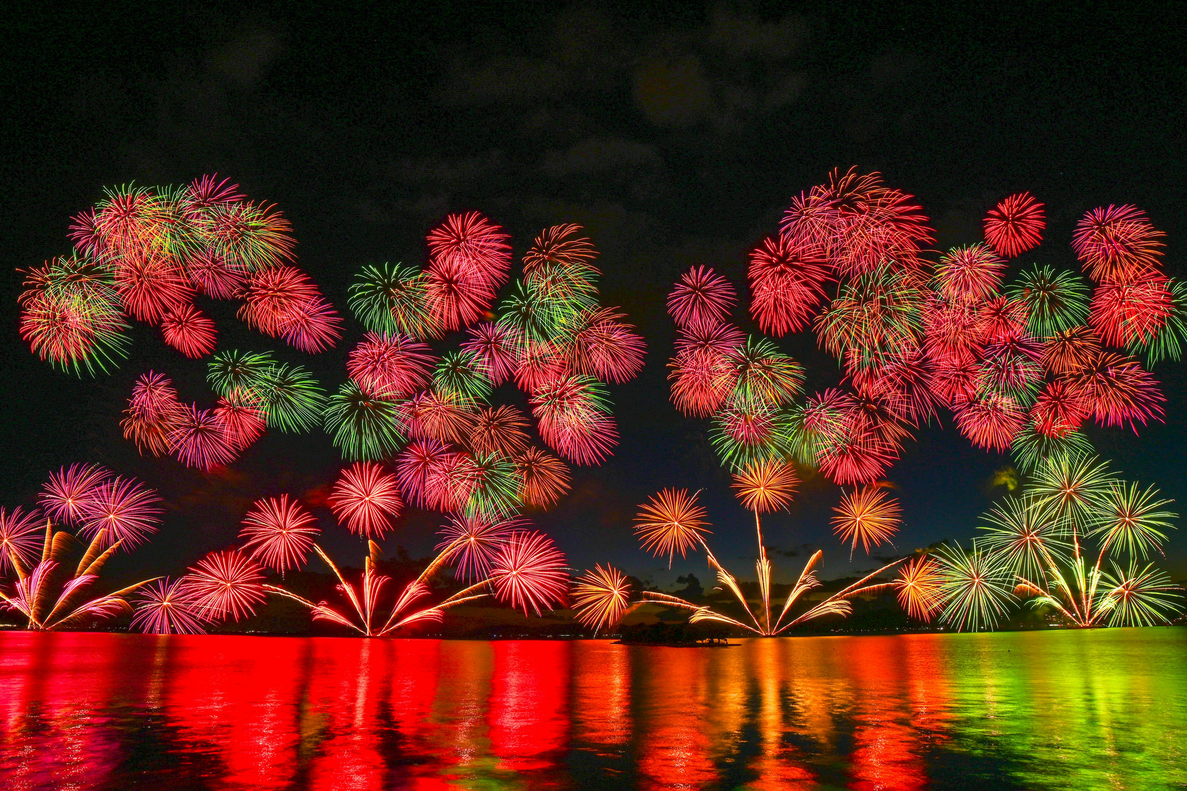 Fuegos artificiales coloridos iluminando el cielo nocturno reflejados en el agua