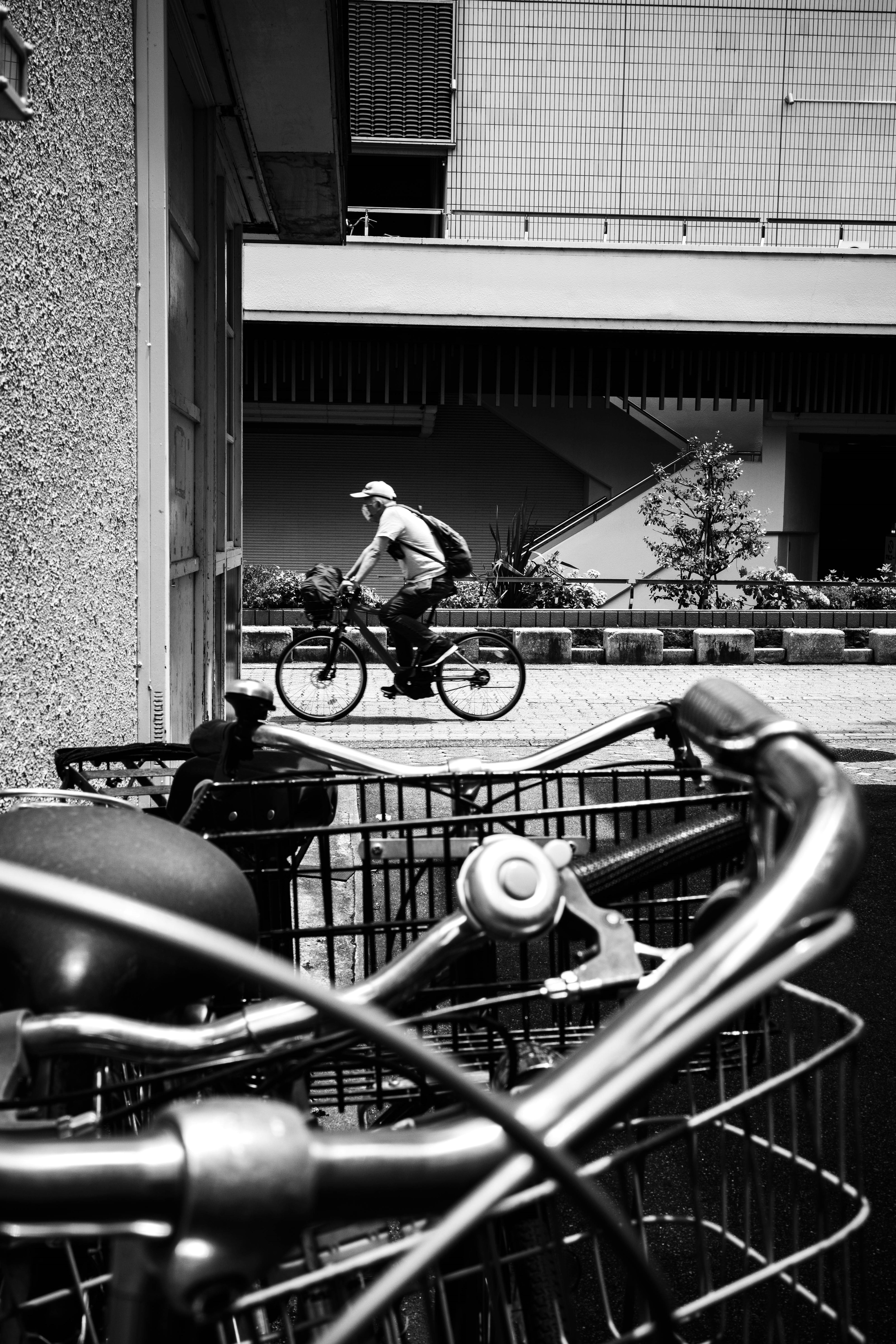 Un hombre montando en bicicleta en blanco y negro con un manillar de bicicleta en primer plano