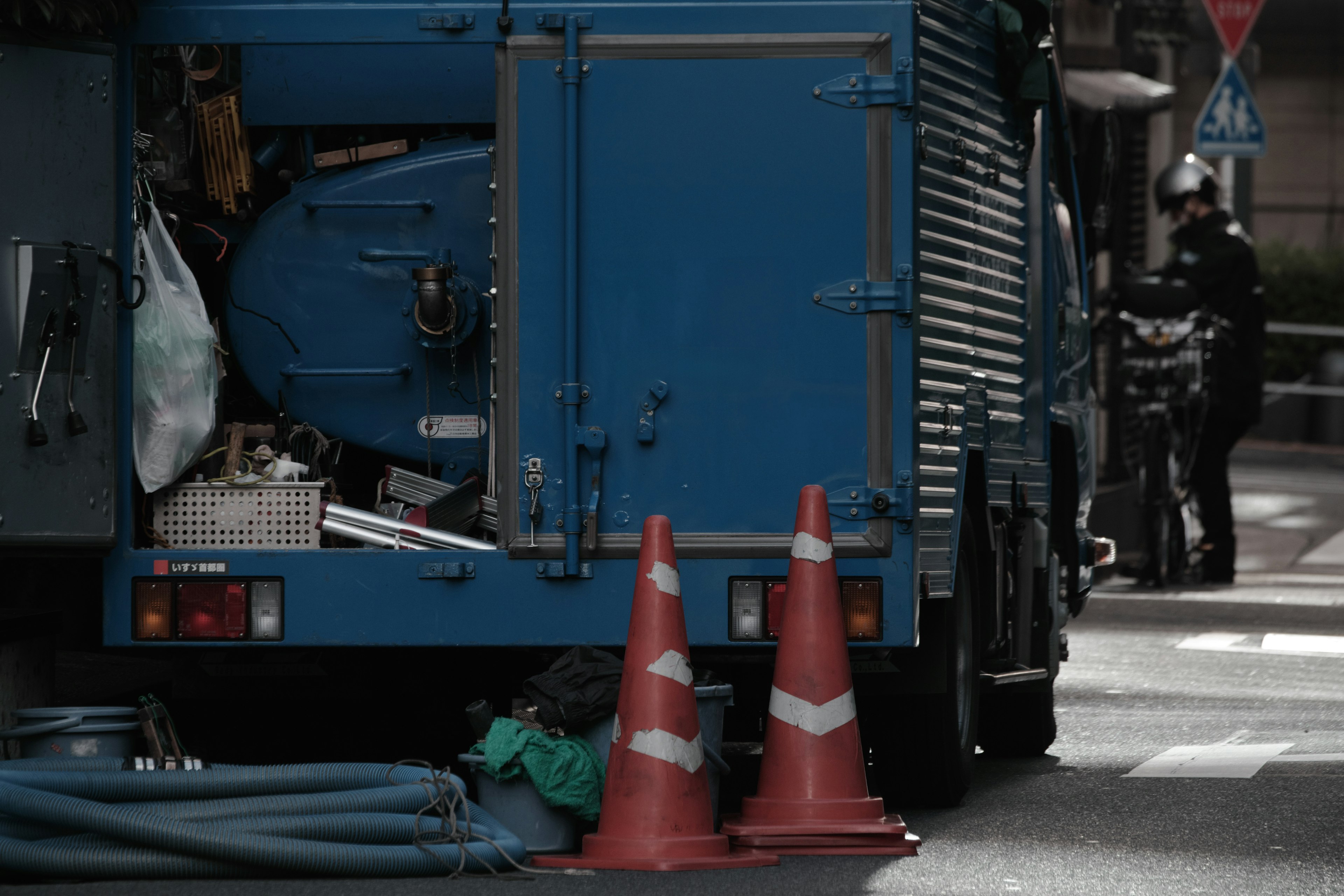 Blue service vehicle with traffic cones in an urban setting