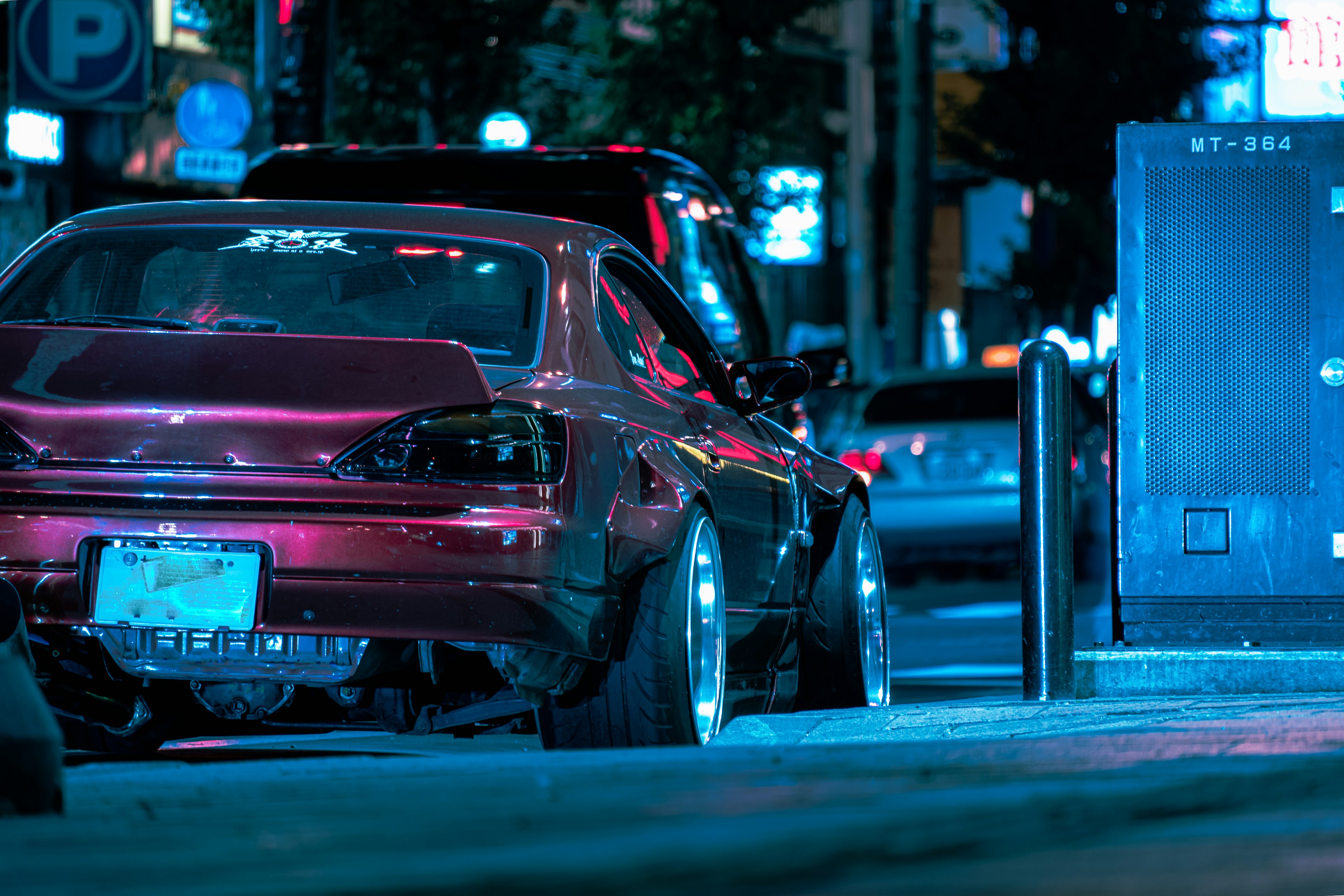 A red sports car reflecting lights in a nighttime urban setting