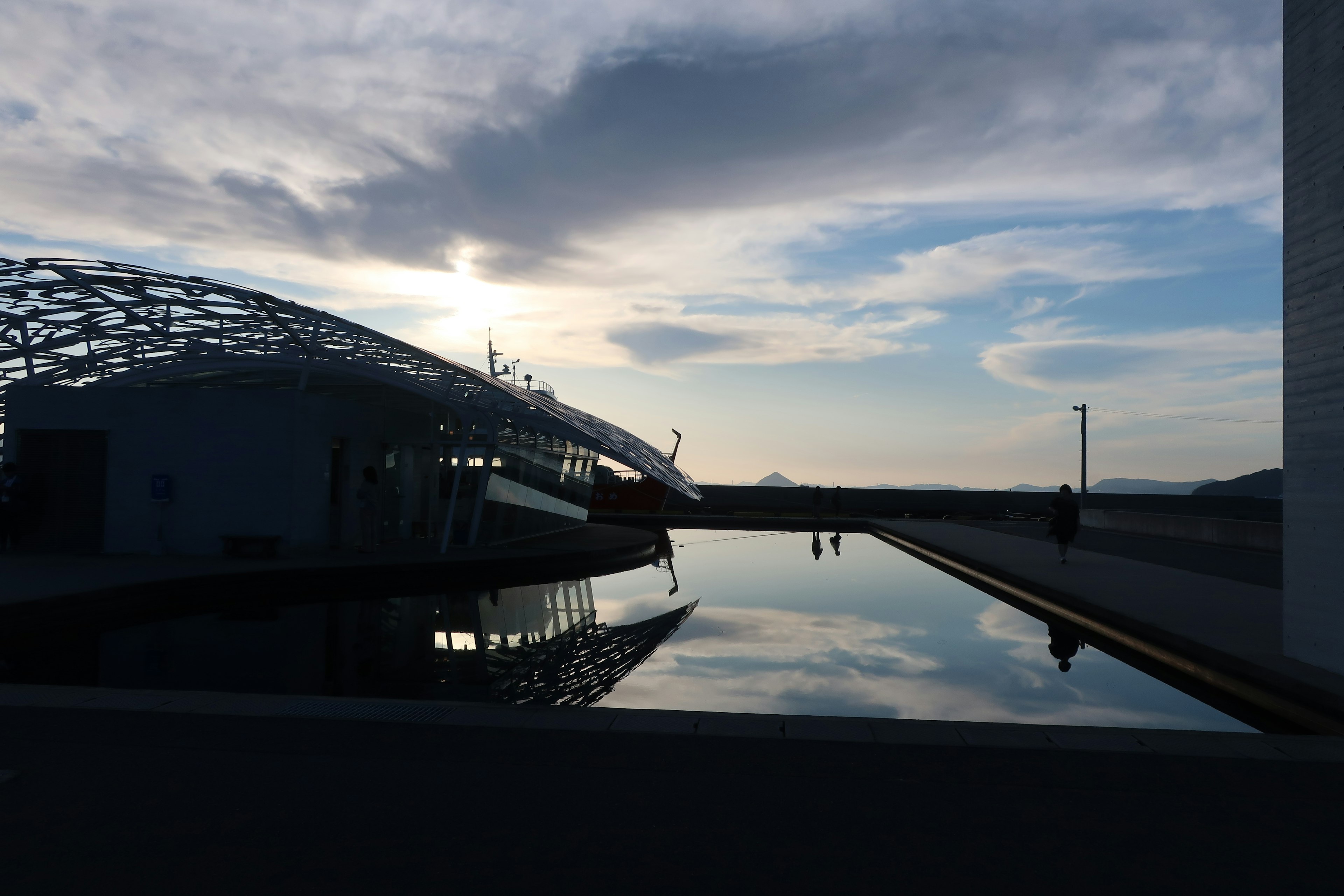 Silhouette di un edificio moderno al crepuscolo con una superficie d'acqua calma