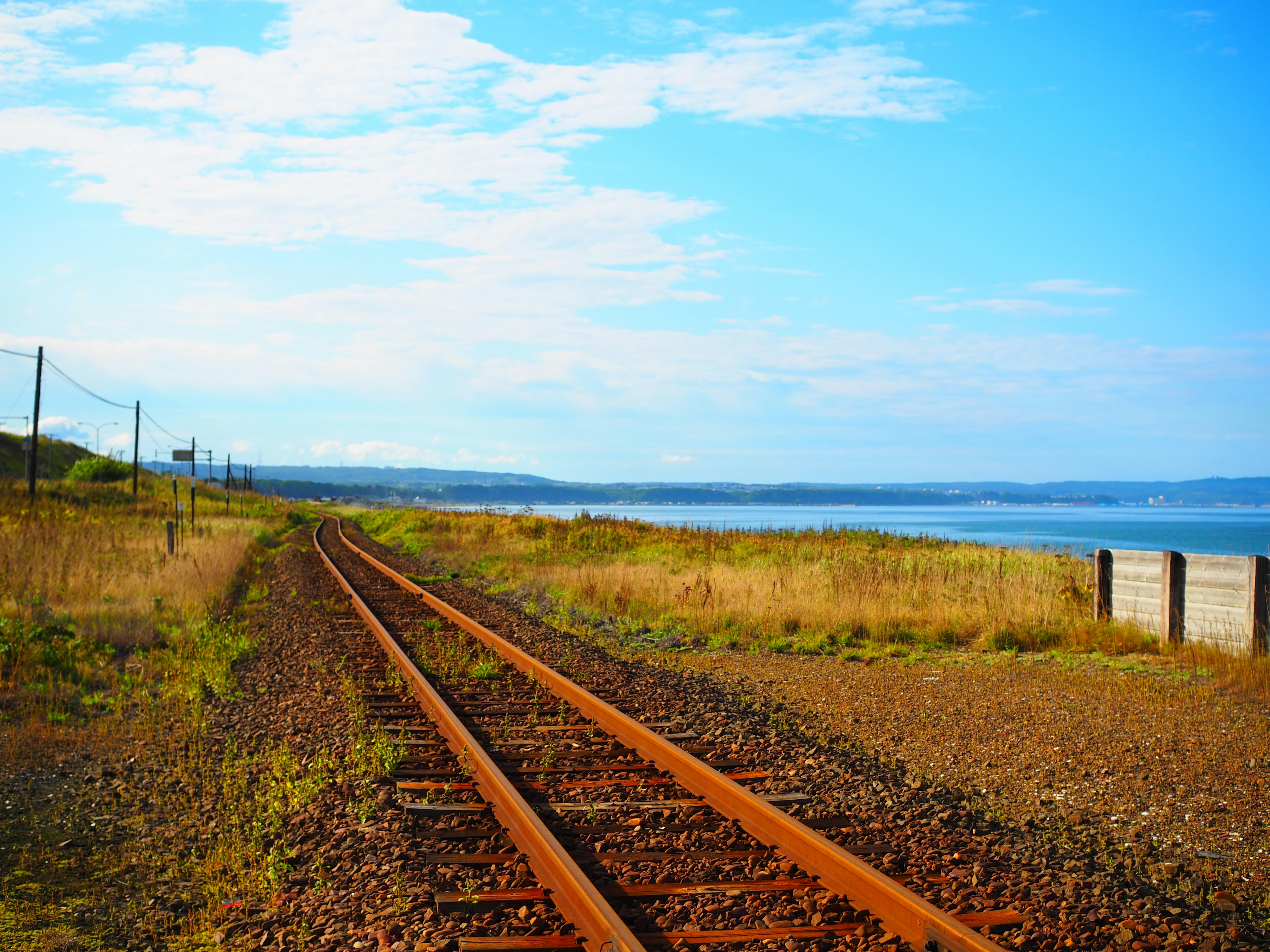 Malersicher Blick auf Bahngleise nahe dem Meer unter einem blauen Himmel