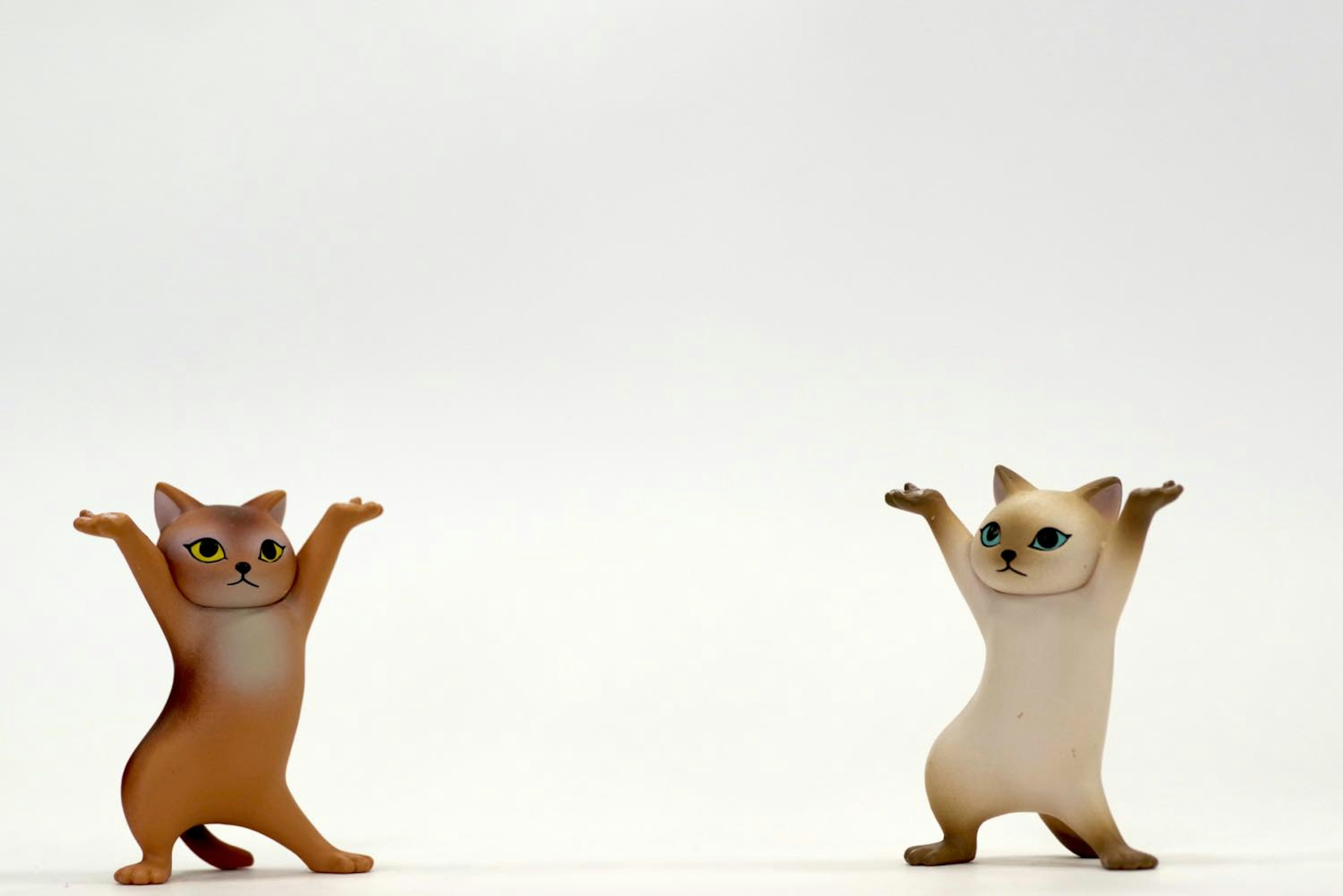 Two cat figurines raising their arms