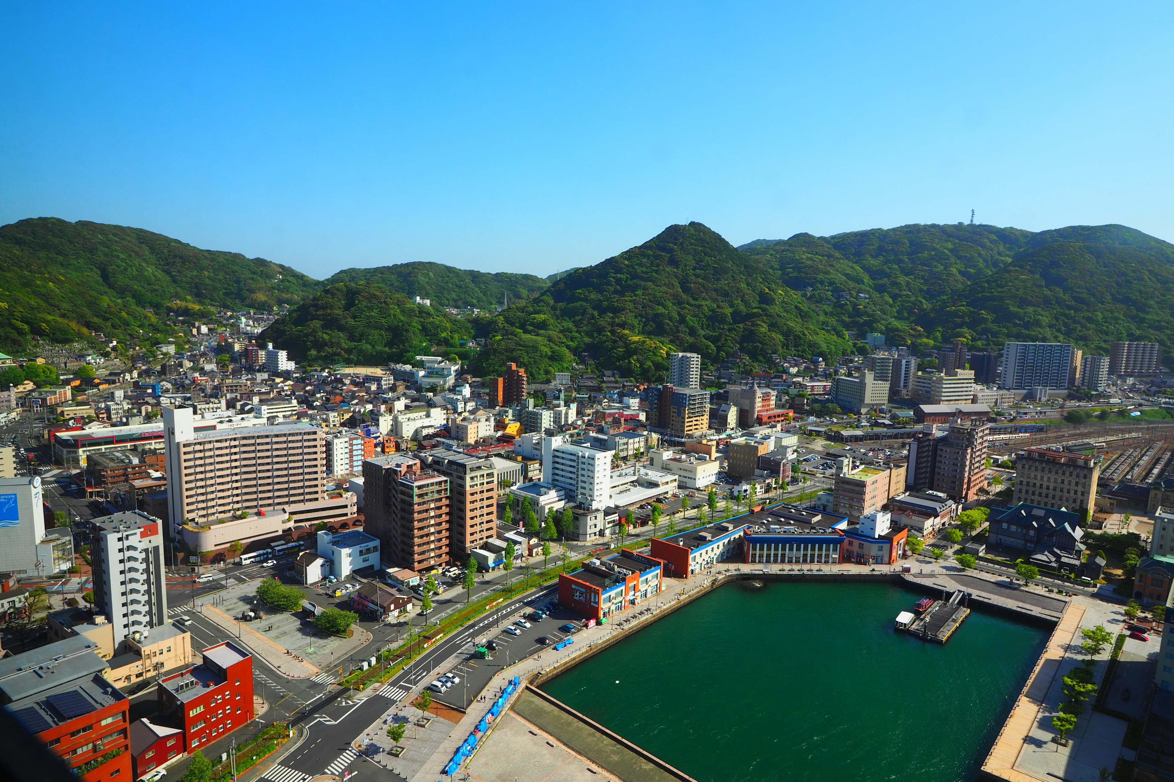 A panoramic view of a coastal town with green hills in the background