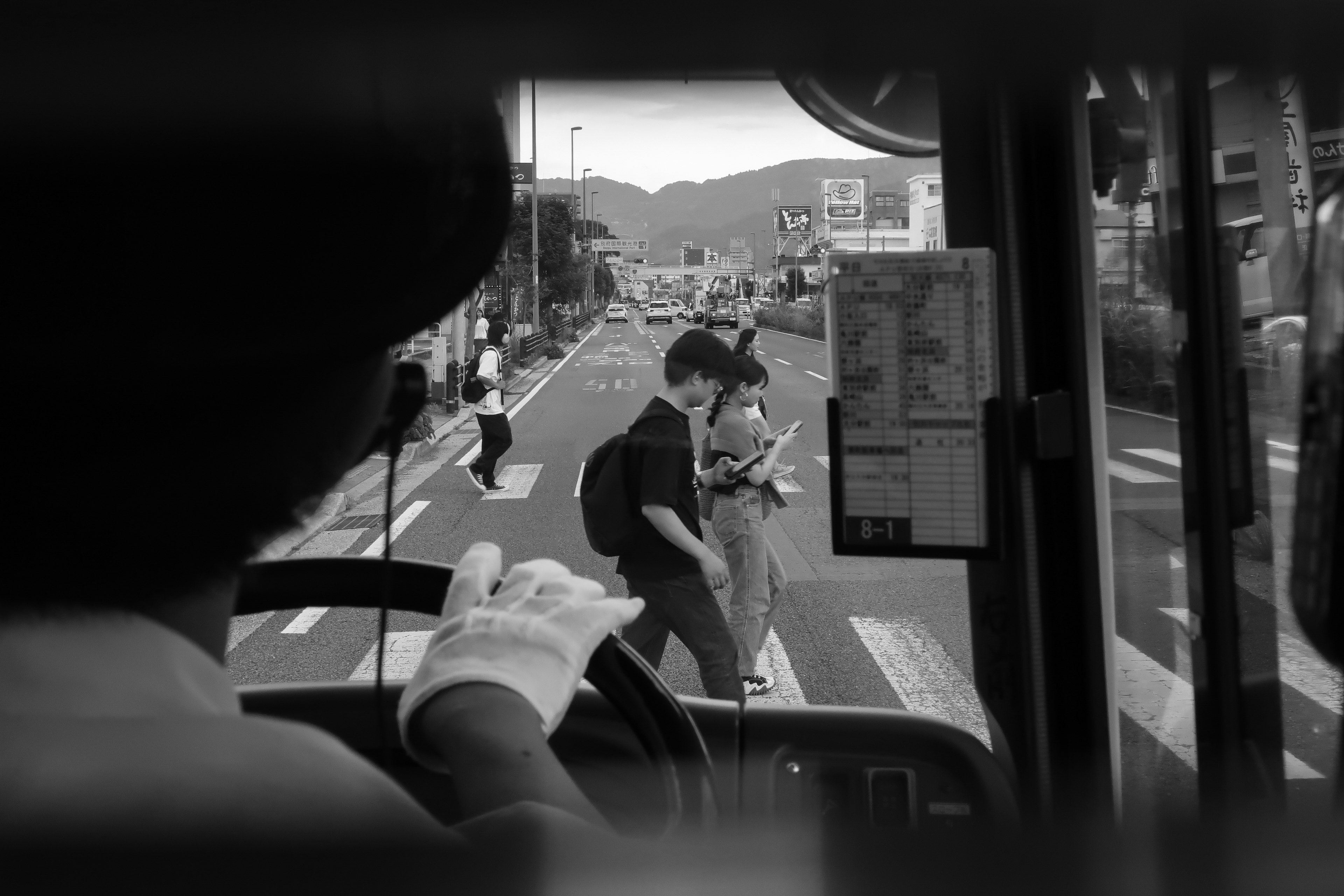 Vista dalla prospettiva di un autista di autobus che mostra una scena di strada con una giovane coppia che attraversa